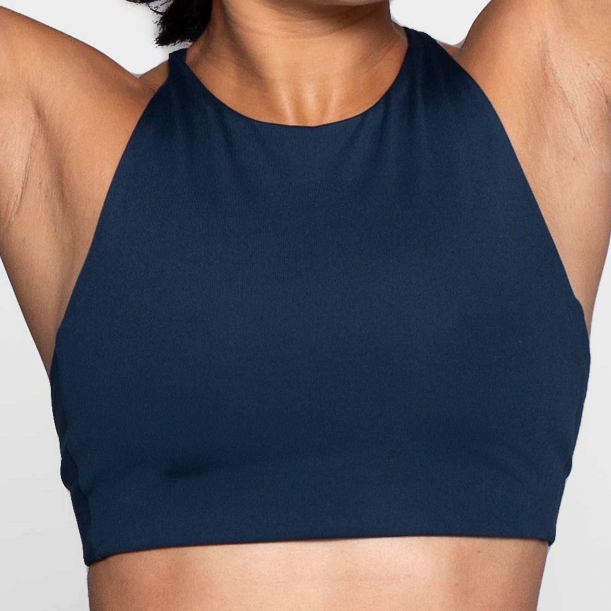 Person trägt ein dunkelblaues Sporttop vor einem weißen Hintergrund.