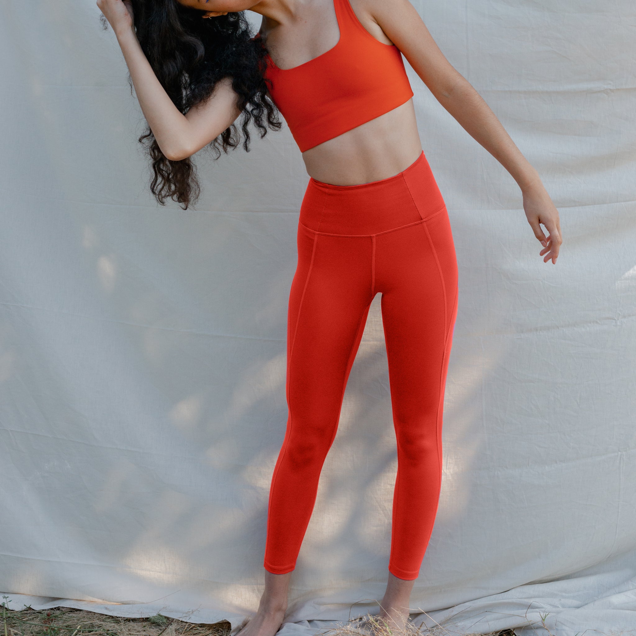 Person in red athletic wear poses in front of a white fabric backdrop.