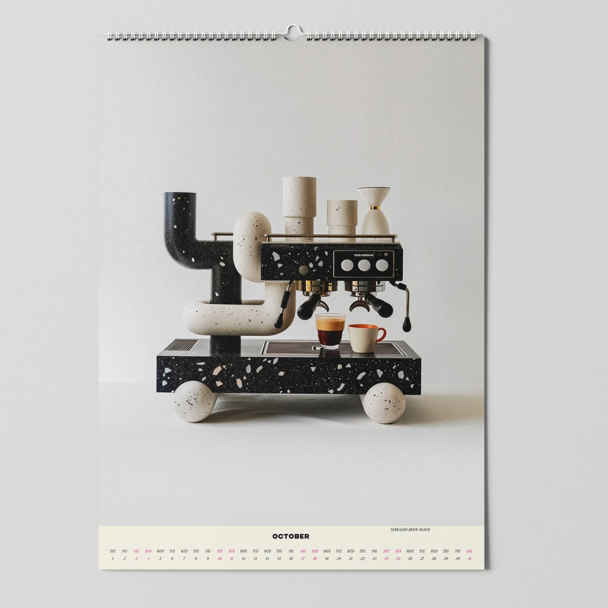 Ein moderner Wandkalender zeigt eine abstrakte, skulpturale Espressomaschine mit Tassen auf einem fahrbaren Untersatz. Die Seite ist bis Oktober geöffnet, mit Daten in kleinem Text unterhalb des Bildes. Der Hintergrund ist minimalistisch und weiß.