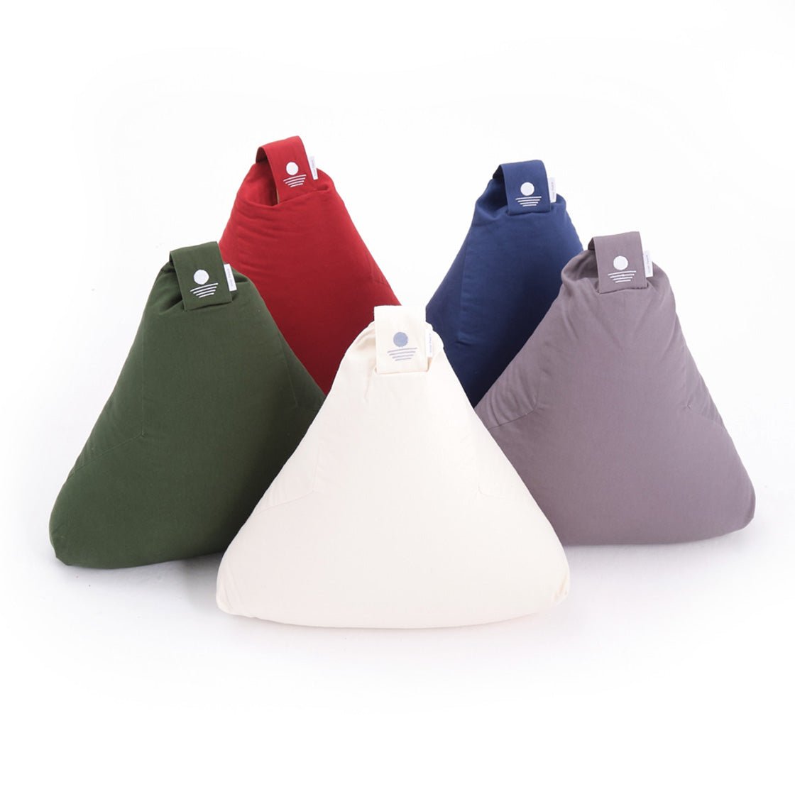 Fünf dreieckige Kissen in verschiedenen Farben (grün, rot, blau, grau, beige) stehen aufrecht nebeneinander.