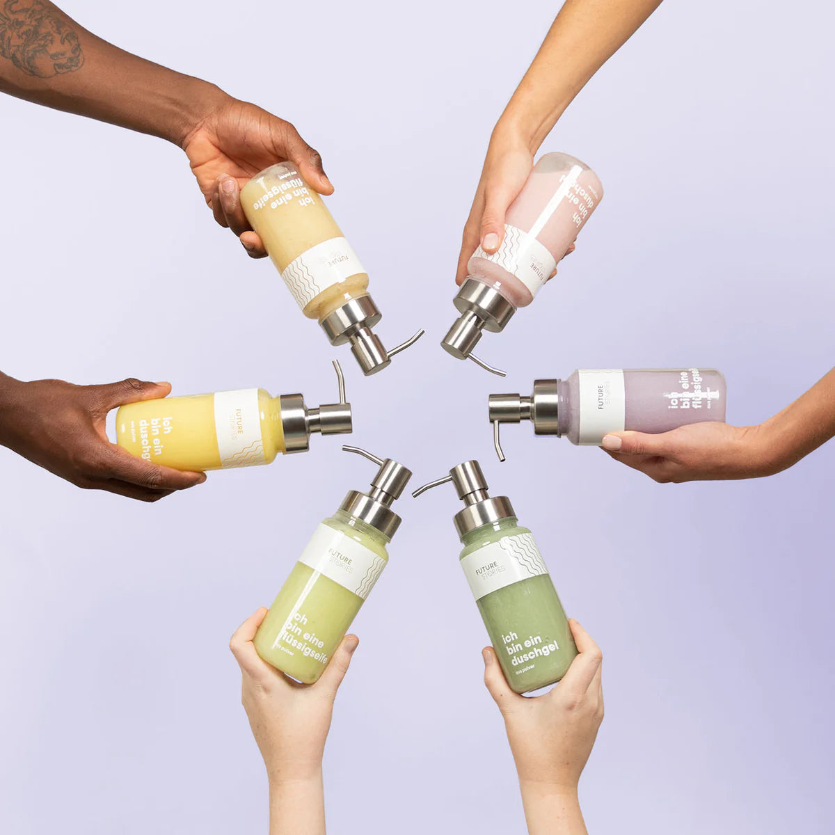 Sechs Hände mit unterschiedlichen Hauttönen halten verschiedenfarbige Flaschen mit Pumpspendern für Handseife, die in einem kreisförmigen Muster vor einem hellvioletten Hintergrund angeordnet sind.