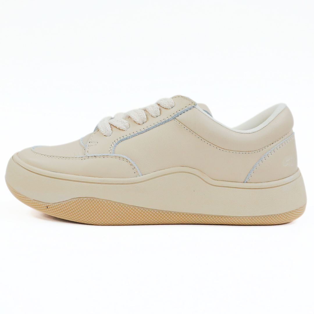Beiger Sneaker mit hellbrauner Sohle und weißen Schnürsenkeln, seitliche Ansicht auf weißem Hintergrund.