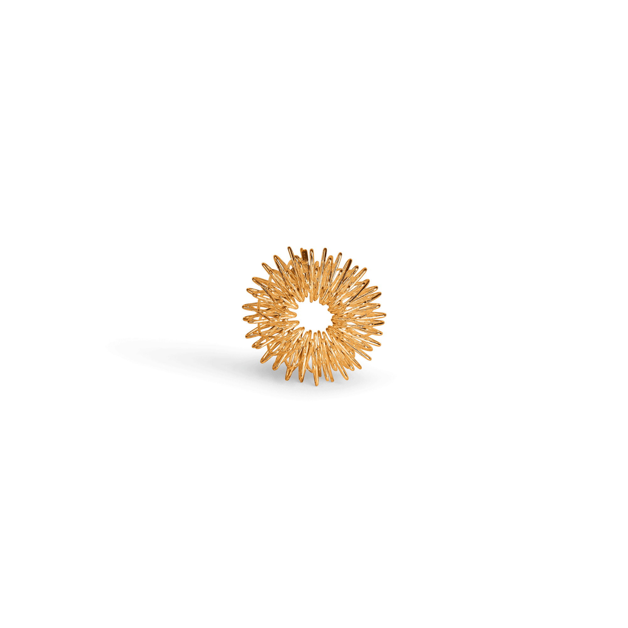 Goldenes stacheliges Objekt in Ringform, das auf einer weißen Oberfläche liegt und einen Schatten wirft.