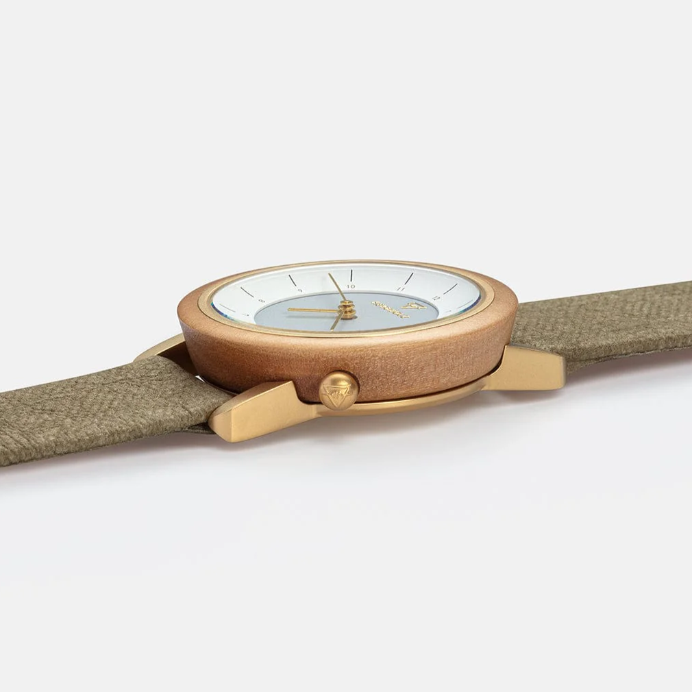 Armbanduhr mit goldenem Gehäuse, weißem Zifferblatt und grünem Stoffarmband, seitlich fotografiert.