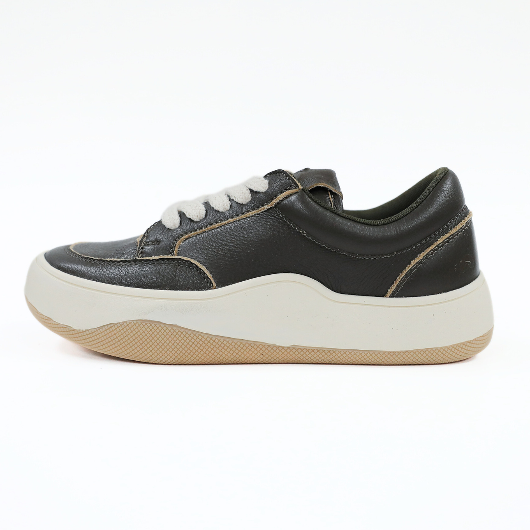 Schwarzer Sneaker mit weißen Schnürsenkeln und beigefarbener Sohle, seitlich fotografiert auf weißem Hintergrund.