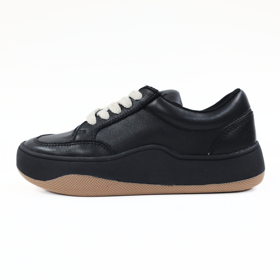 Schwarzer Sneaker mit weißen Schnürsenkeln und brauner Sohle, seitlich gezeigt auf weißem Hintergrund.