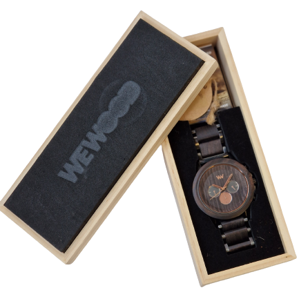 Eine hölzerne Armbanduhr mit dunkelbraunem Zifferblatt und Armband befindet sich in einer offenen rechteckigen Schachtel mit dem Aufdruck WEWOOD auf dem schwarzen Deckel, der leicht schief neben der Schachtel liegt.