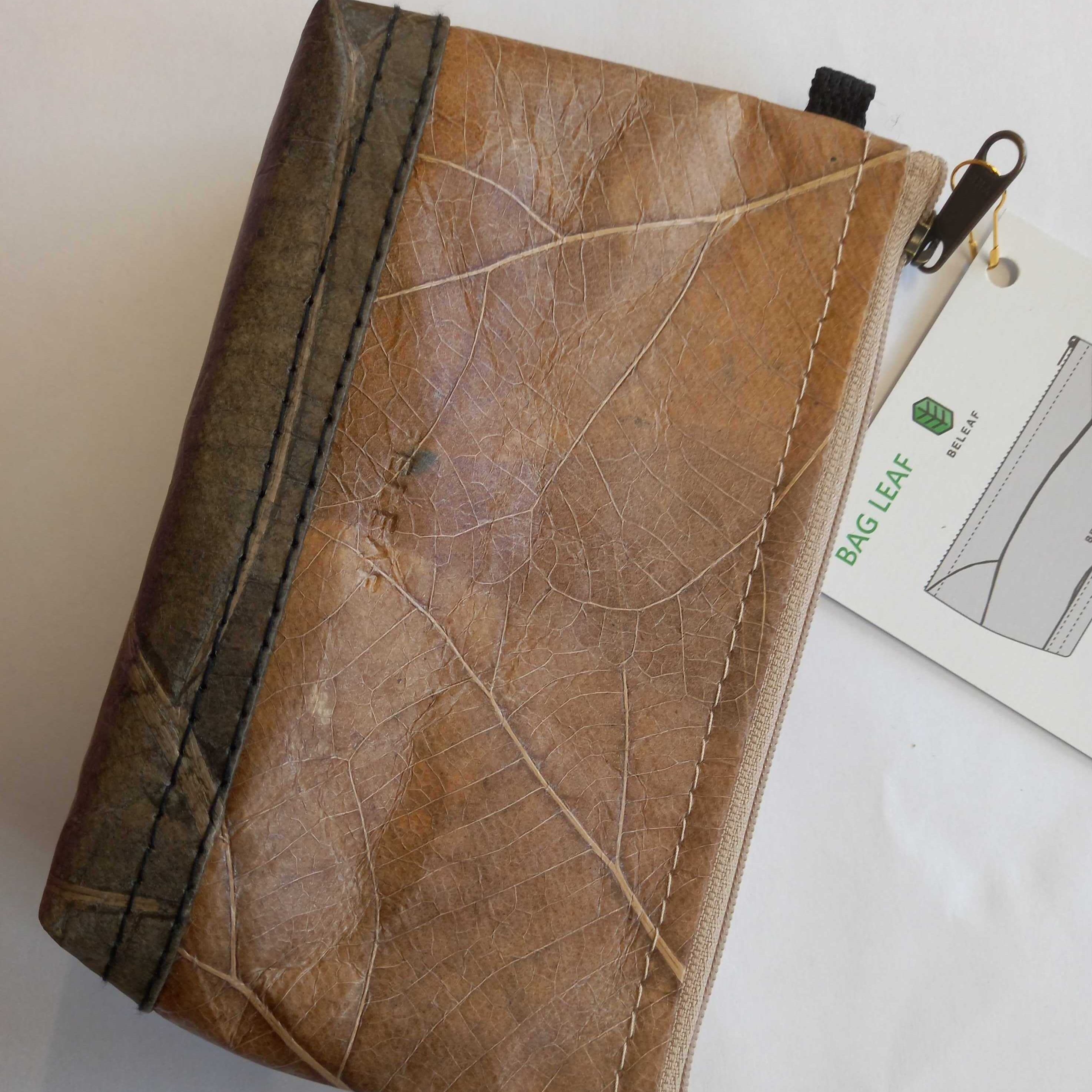 Braune Tasche mit Blattstruktur, begleitet von einem Etikett mit der Aufschrift "BAG LEAF" und Produktdarstellung.