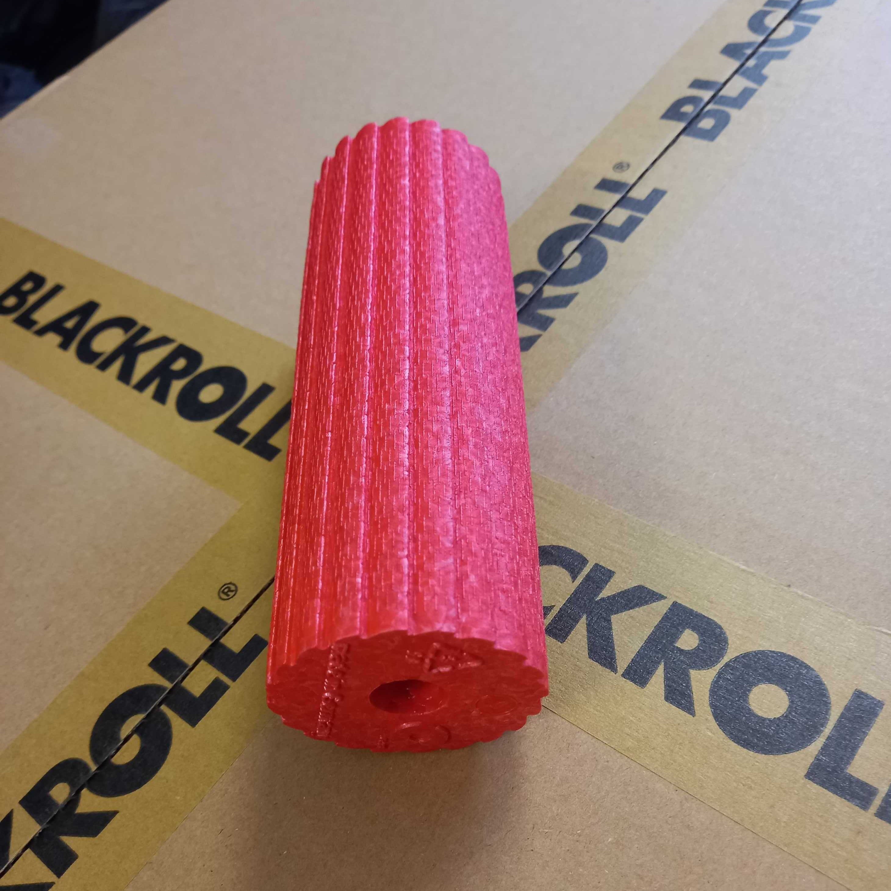 Rote Schaumstoffrolle liegt auf einem Karton mit der Aufschrift „BLACKROLL“.