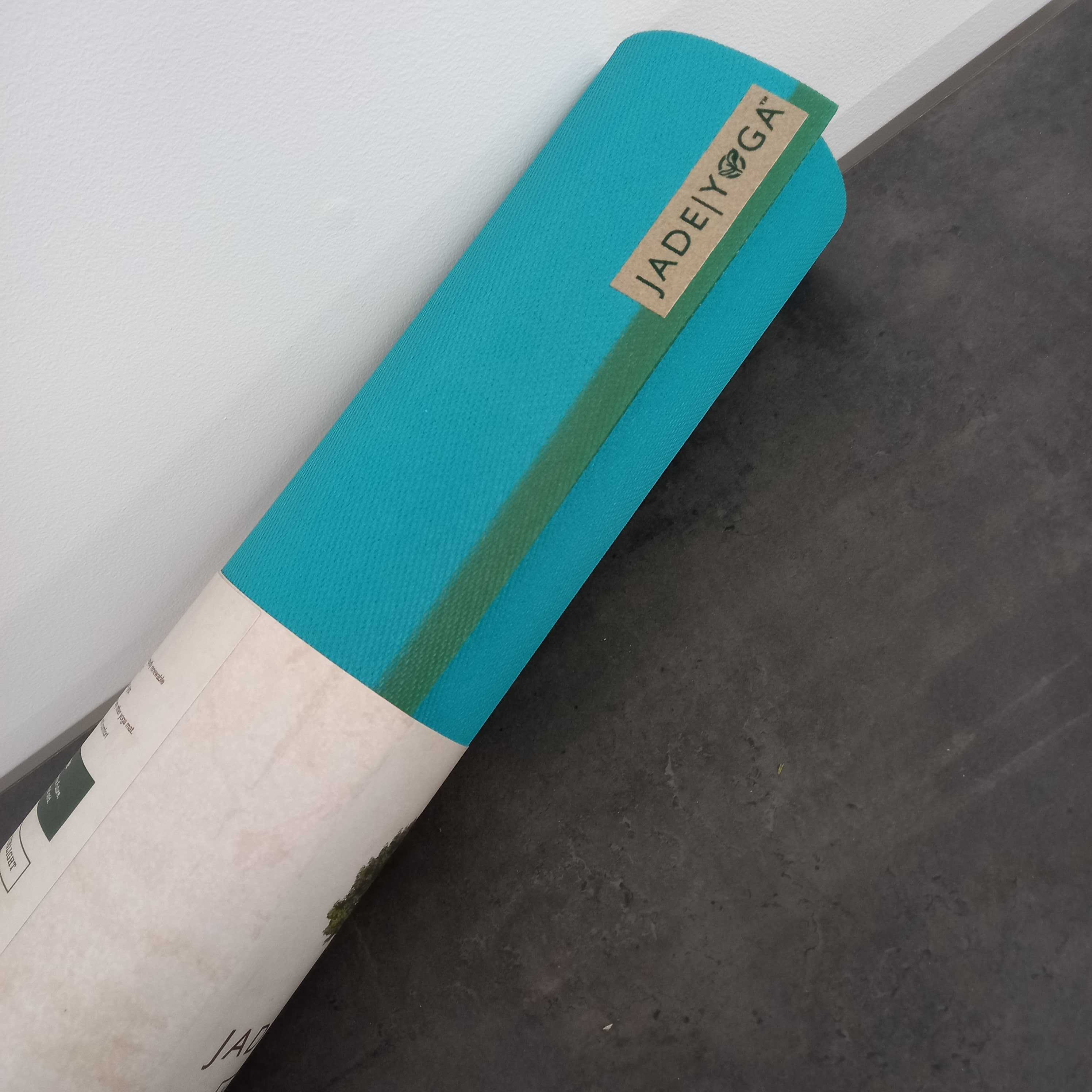 Eine zusammengerollte blaue Yogamatte mit einem Label auf grauem Boden.