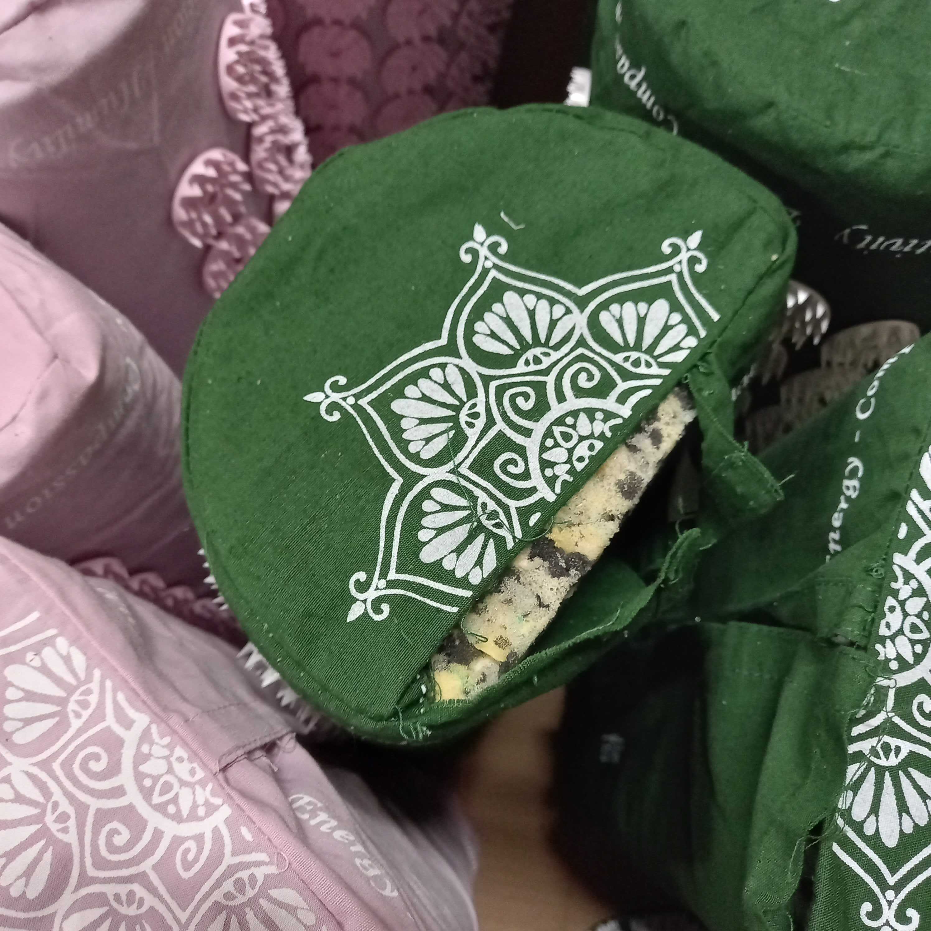 Grüne und lila Stoffbezüge mit weißem Muster, die über runden Gegenständen gespannt sind.