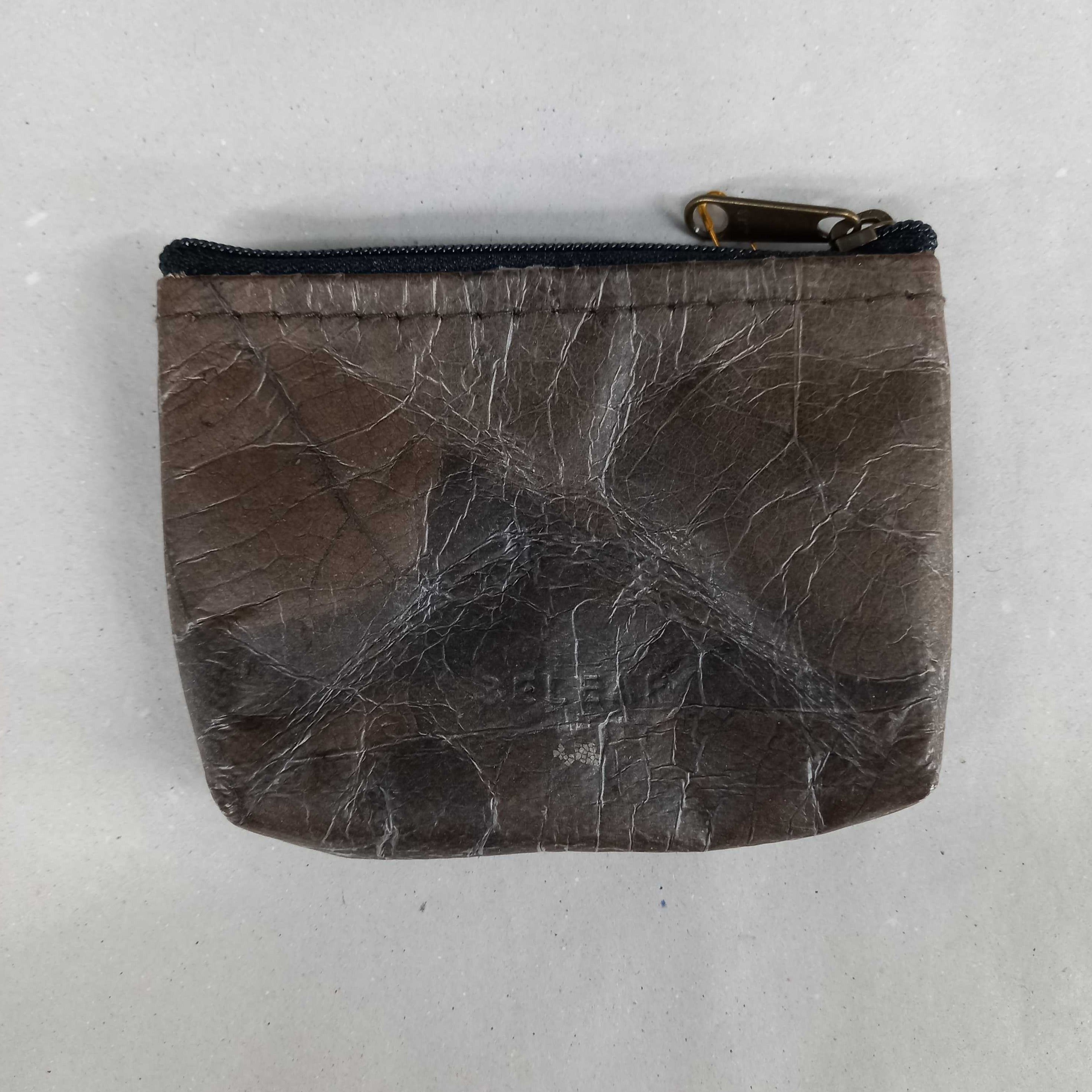 Braunes Etui mit Reißverschluss und sichtbaren Gebrauchsspuren auf einer weißen Oberfläche.