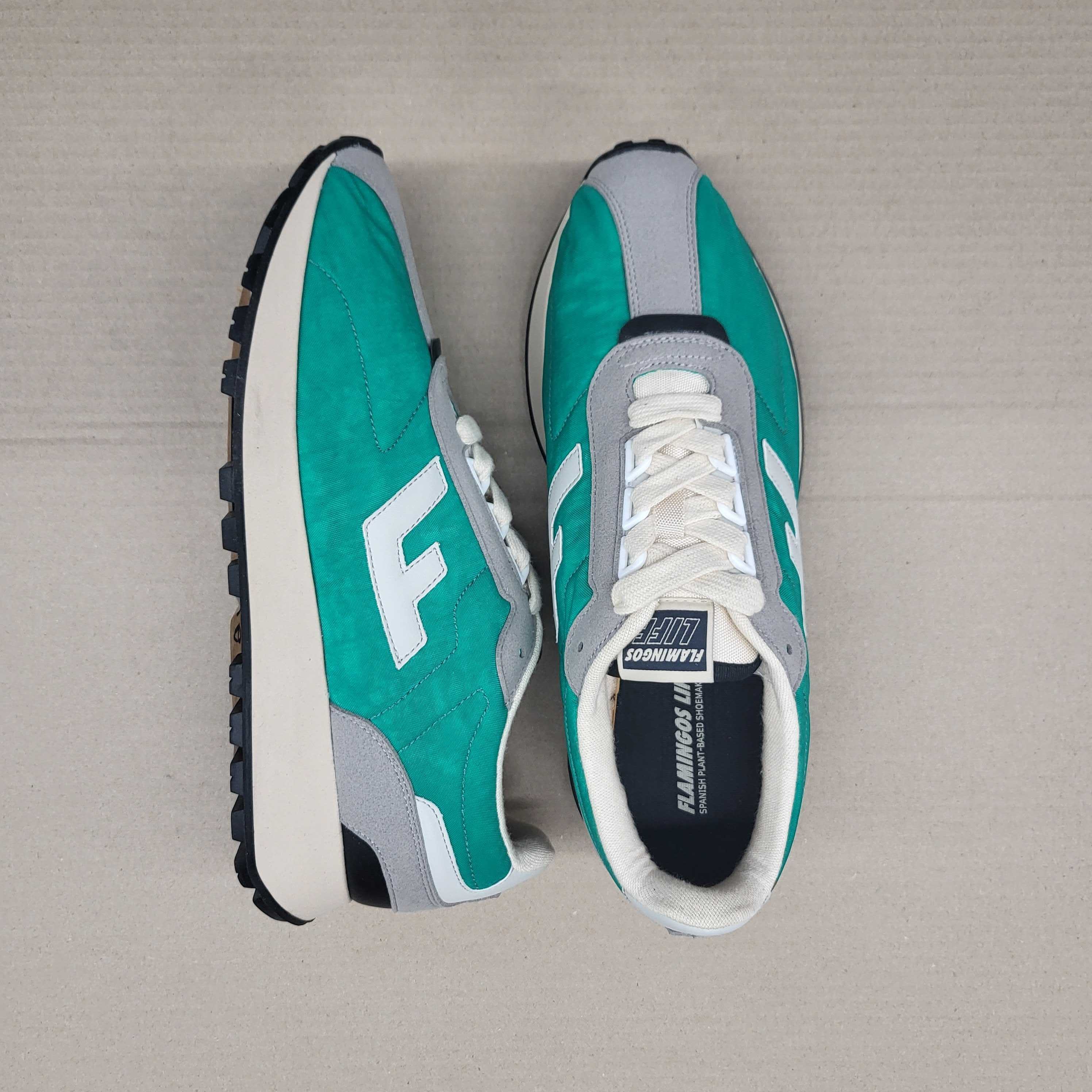 Turquoise and grey sneakers on a beige surface, with white laces and a prominent "F" logo on the side.