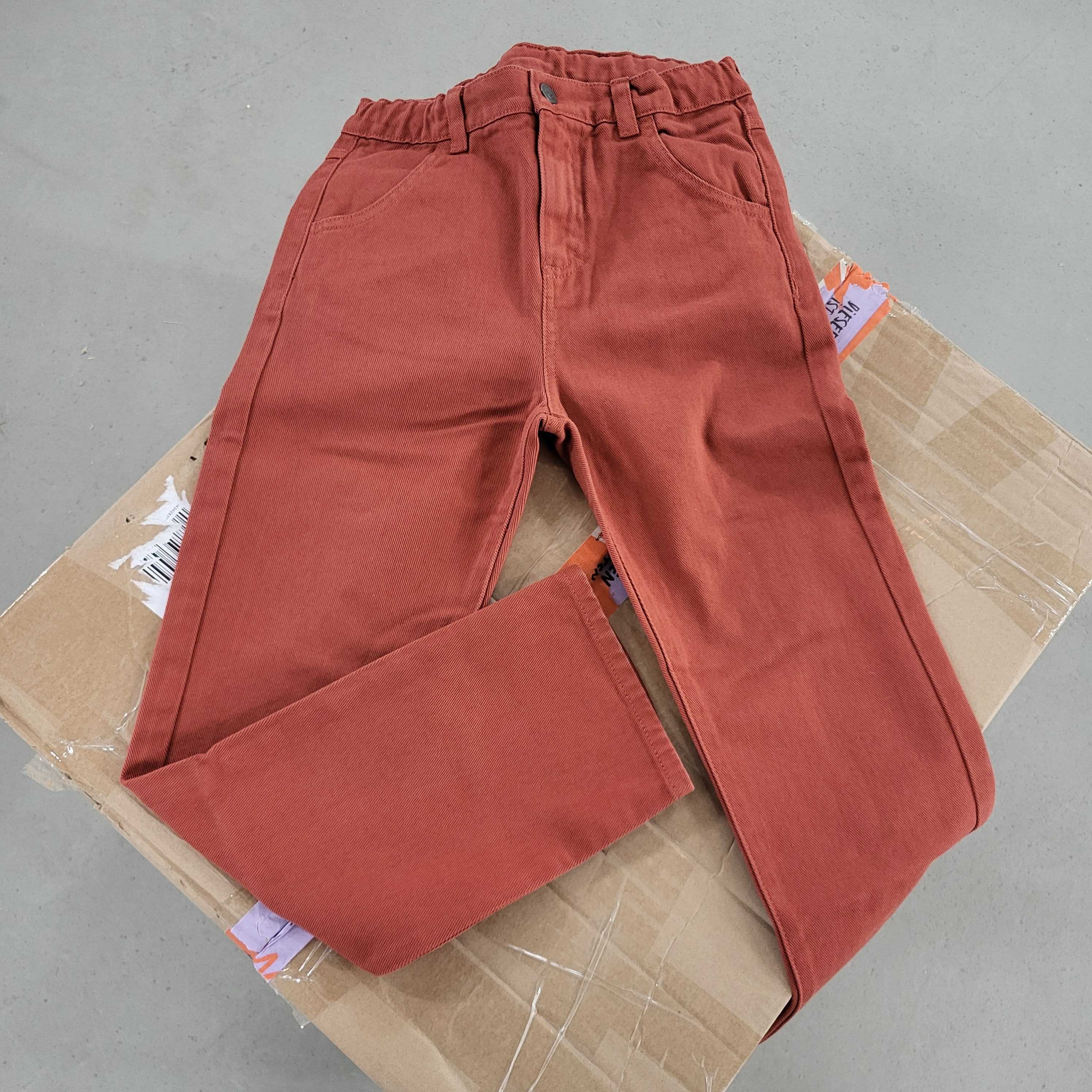 Rote Hose mit elastischem Bund liegt auf einem Kartonboden.