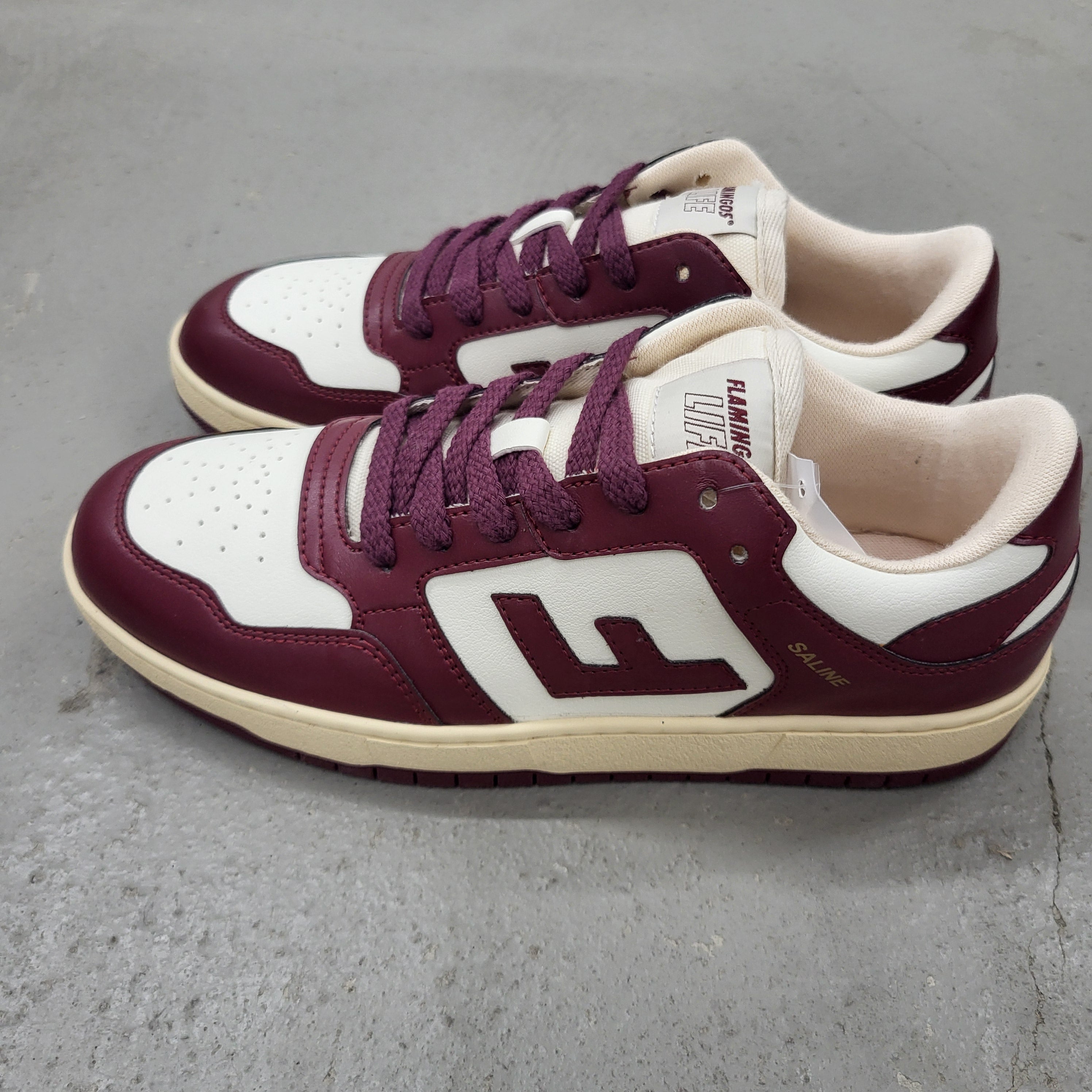 Ein Paar kastanienbraune und weiße Turnschuhe mit F-Logos an den Seiten, kastanienbraunen Schnürsenkeln und beigen Sohlen, die auf einer grauen Fläche angebracht sind. Der linke Schuh hat FLAMINGO LINX und SAMPLE Text auf der Zunge und der Seite.