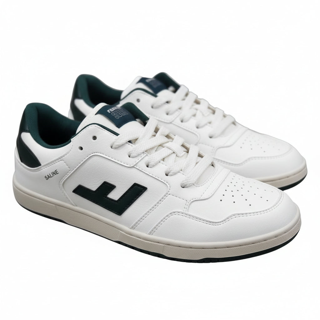 Ein Paar weiße Sportschuhe mit dunkelgrünen Akzenten und schwarzen Sohlen auf einer grauen Oberfläche. Die Schuhe verfügen über ein fettes schwarzes L-Logo an den Seiten und das Wort SALVE in der Nähe der Ferse gedruckt.