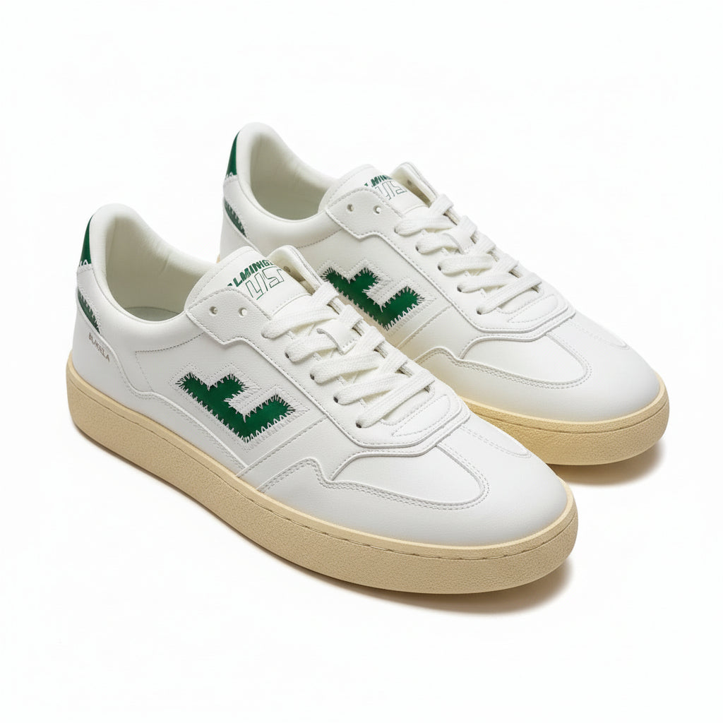 Ein Paar weiße Turnschuhe mit grünen Akzenten, mit einem grünen L-Logo an der Seite und dem Wort BURELA in der Nähe der Ferse, die auf einer glatten grauen Oberfläche ruhen.