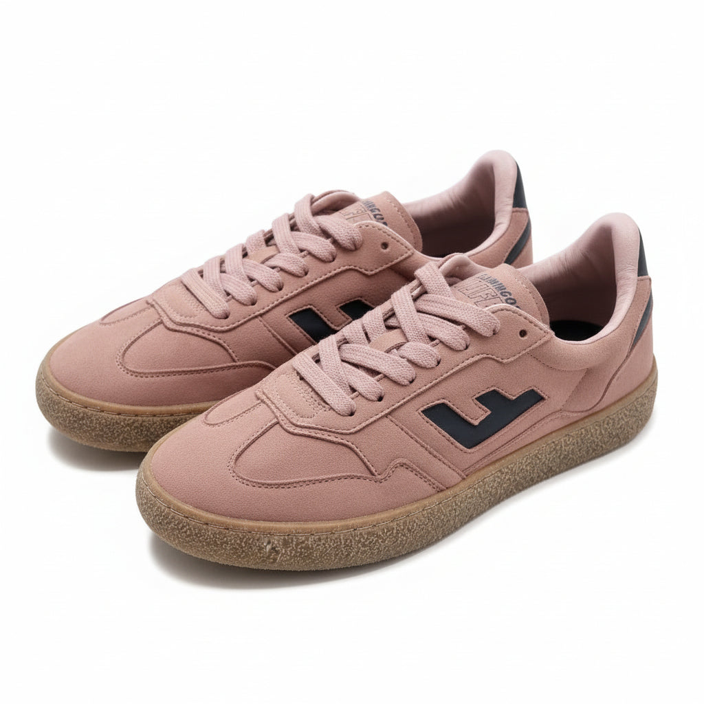 Ein Paar rosa Wildleder-Sneaker mit Gummisohle und dunkelblauen Logo-Akzenten, die nebeneinander auf einem grauen Boden stehen.