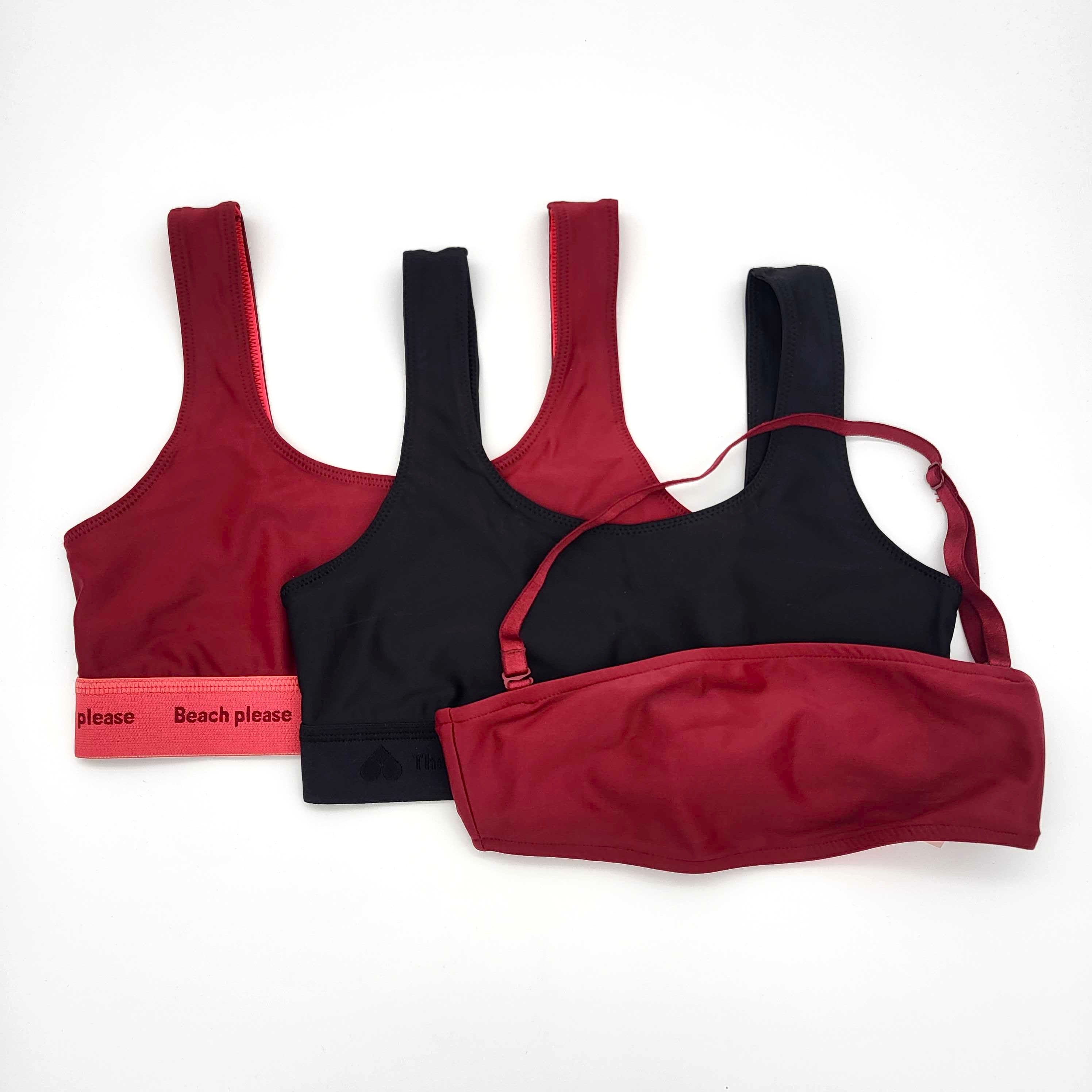 Auf einem weißen Hintergrund sind drei BHs abgebildet: zwei rote Sport-BHs, ein schwarzer Sport-BH und ein roter Bandeau-BH mit verstellbarem Träger.