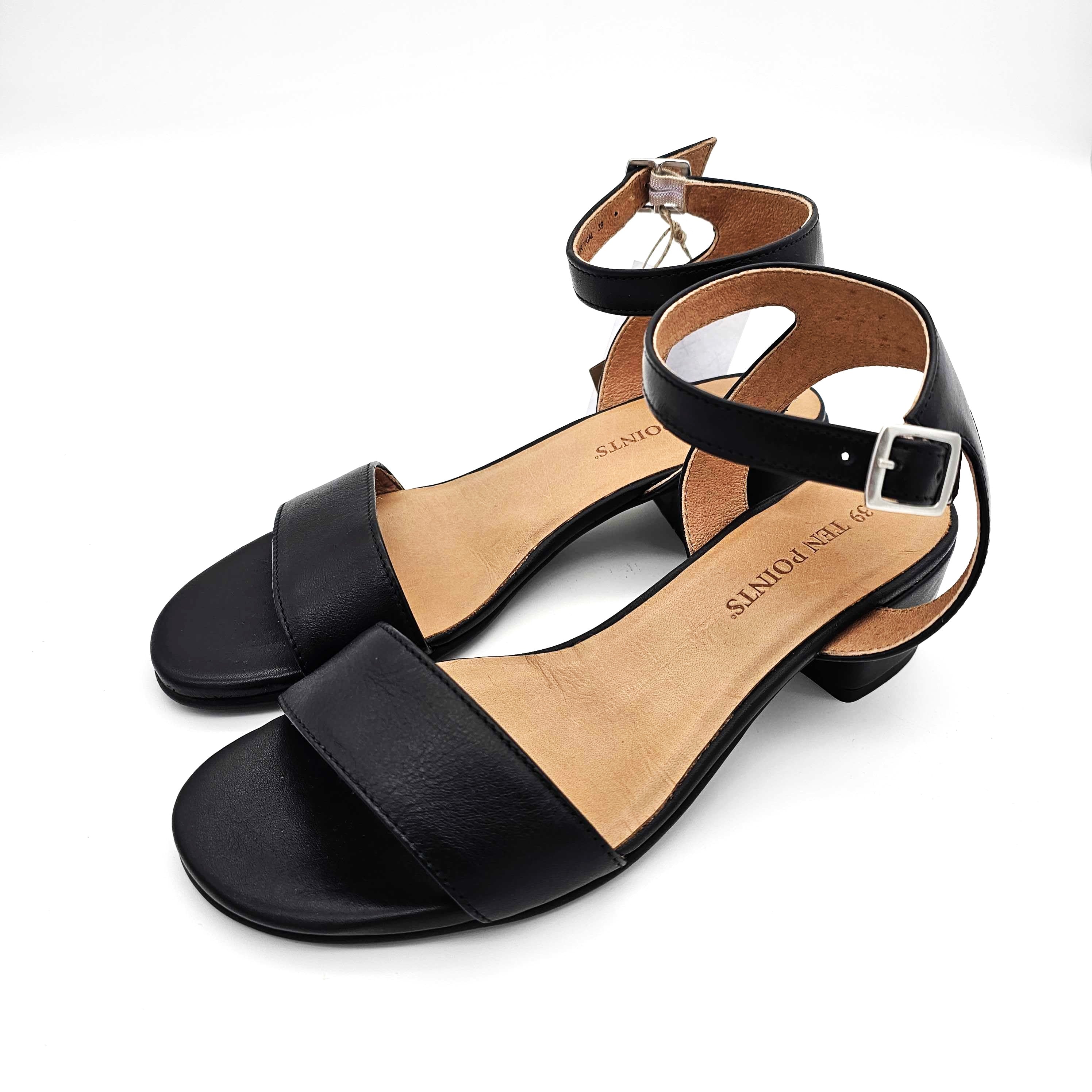 Ein Paar schwarzer, zehenoffener Sandalen mit Knöchelriemen und kleinem Absatz, mit silbernen Schnallen und hellbraunen Sohlen, dargestellt auf weißem Hintergrund.