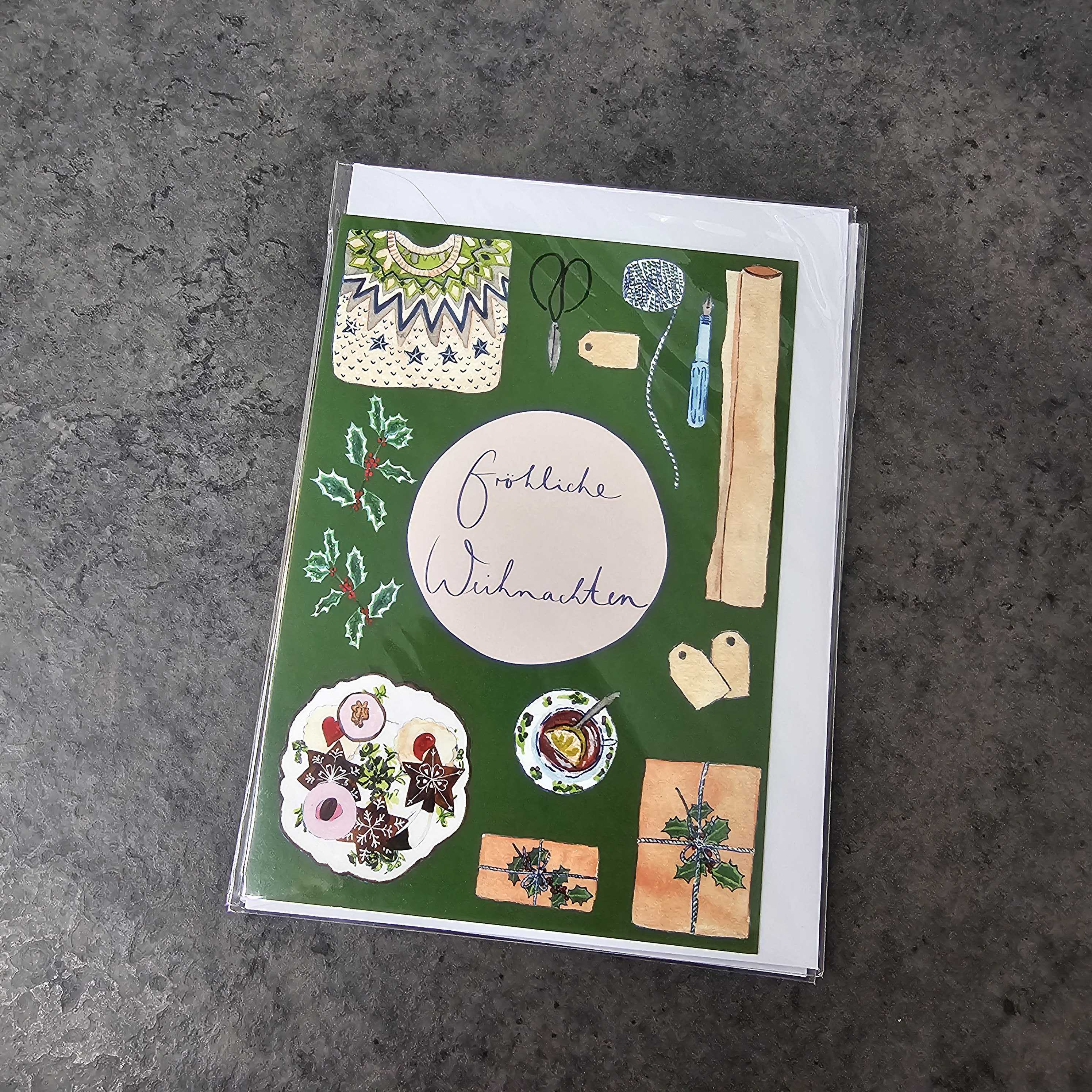 Eine Weihnachtskarte mit der Aufschrift "Fröhliche Weihnachten" in der Mitte, umgeben von festlichen Illustrationen von Stechpalmen, Plätzchen, Ornamenten, Scheren, Schnüren, Backwerkzeugen und Geschenkanhängern auf grünem Hintergrund.