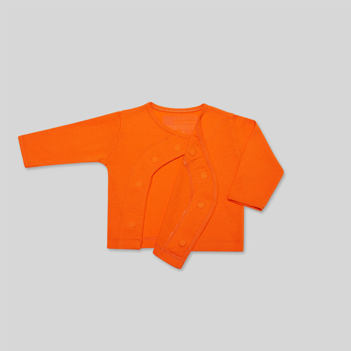 Orangefarbener Baby-Cardigan mit offenen Druckknöpfen, auf grauem Hintergrund liegend.