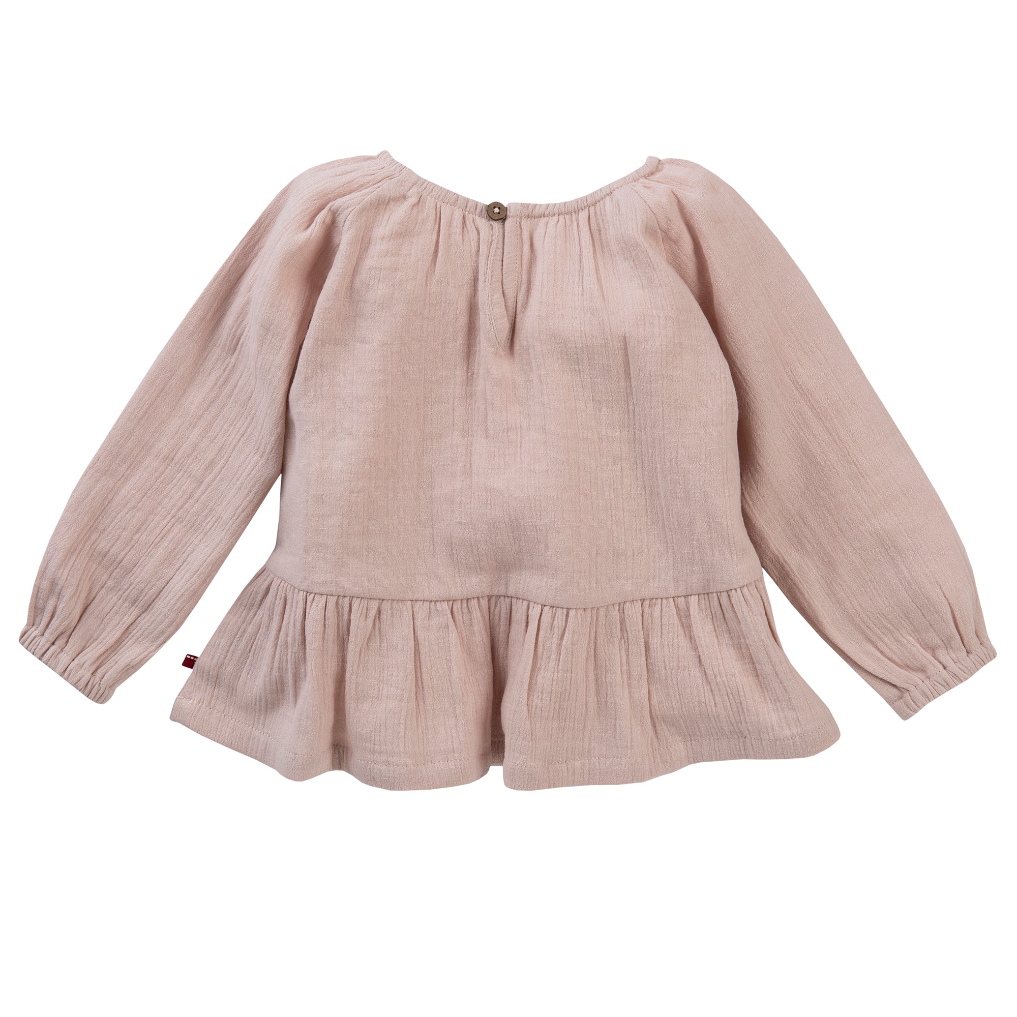 Hellrosa langärmelige Bluse für Kinder mit rundem Ausschnitt, gerafften Details, gerüschtem Saum und Knopfverschluss auf der Rückseite. Der Stoff hat eine weiche, leicht gekräuselte Textur.