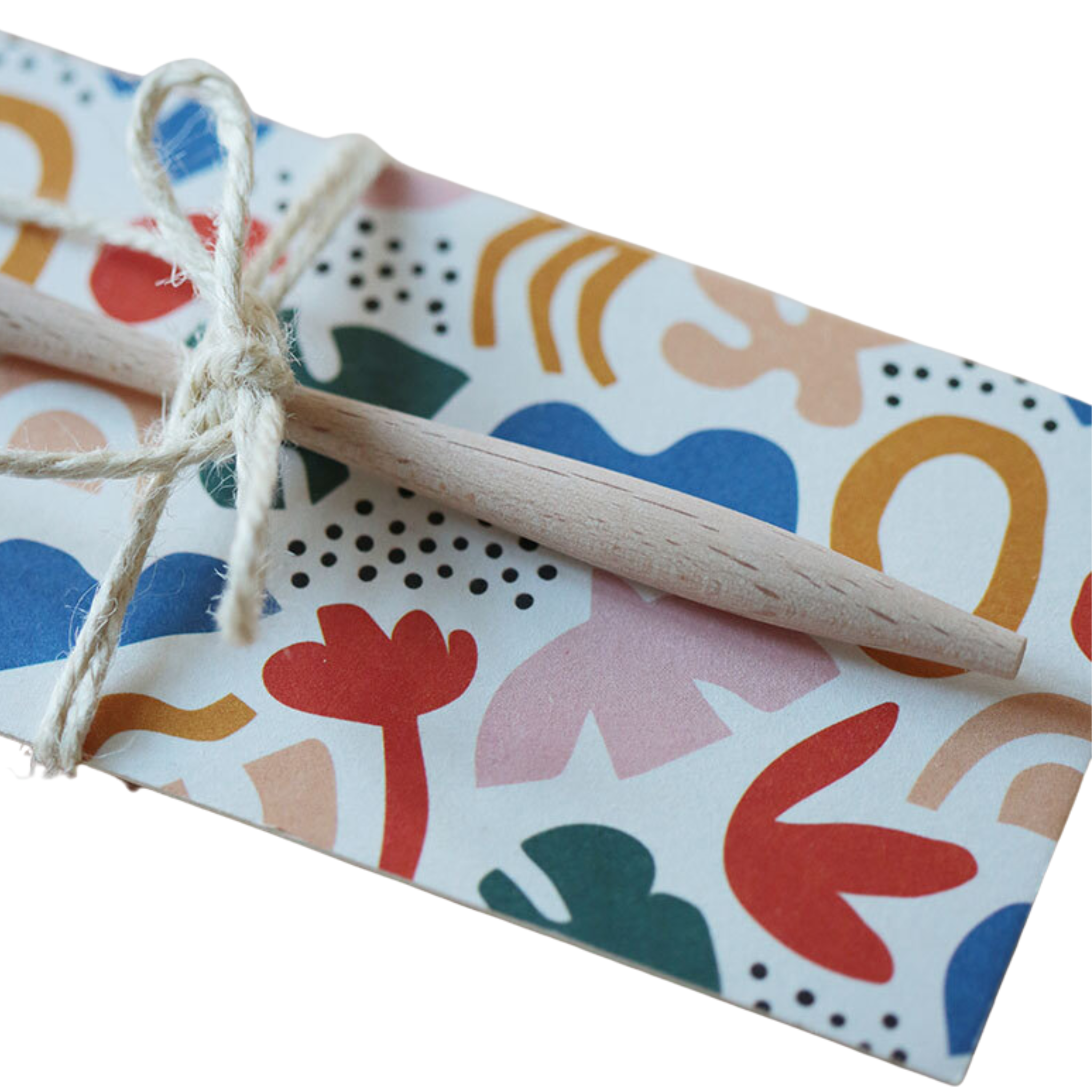 Ein farbenfroher, abstrakt gemusterter Umschlag, der mit einer Schnur verschnürt ist und an dessen Spitze ein Bleistift befestigt ist. Das Design zeigt Formen in Rot, Blau, Grün, Gelb und Rosa auf einem weißen Hintergrund.