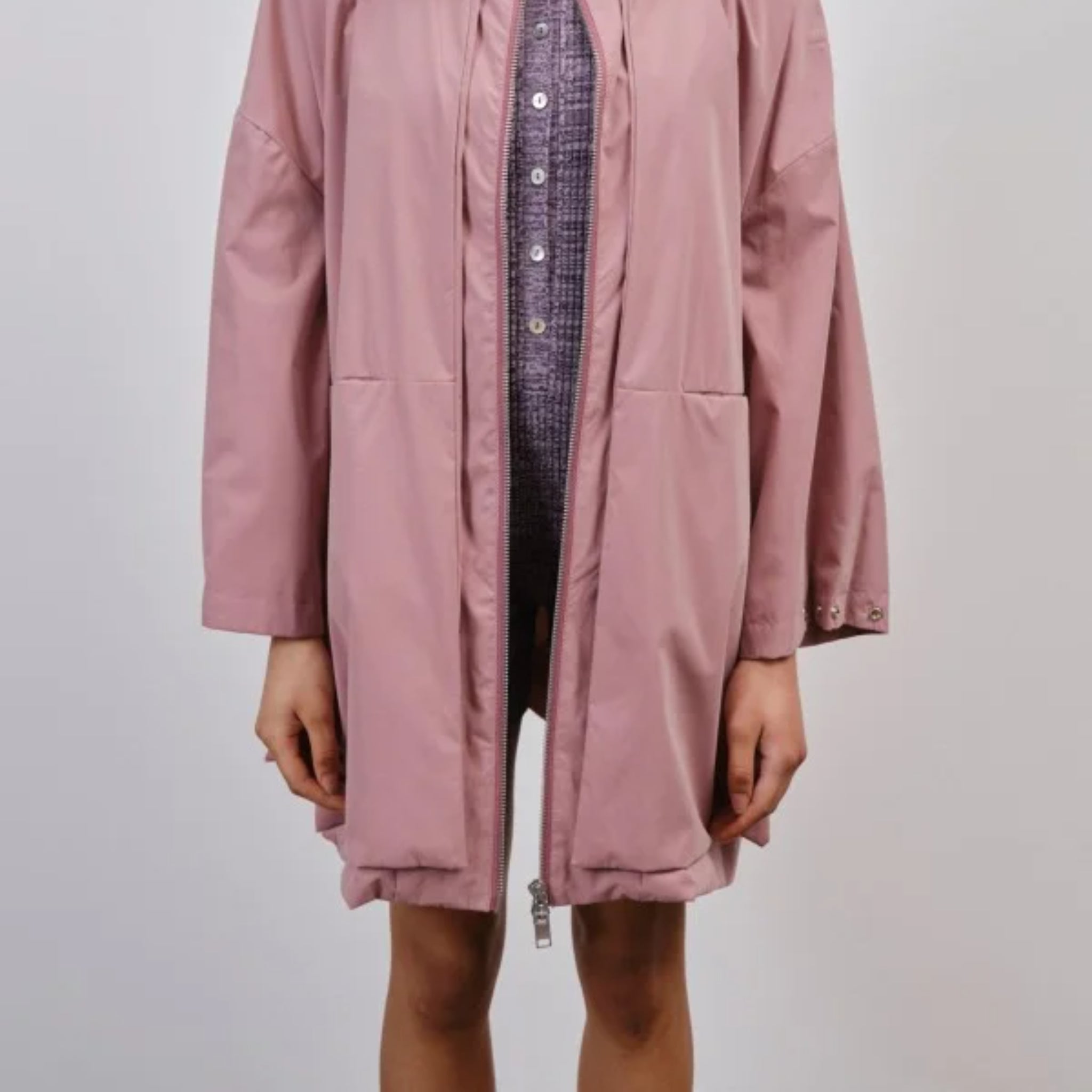 Person in einem offenen rosafarbenen Mantel mit Knöpfen darunter.