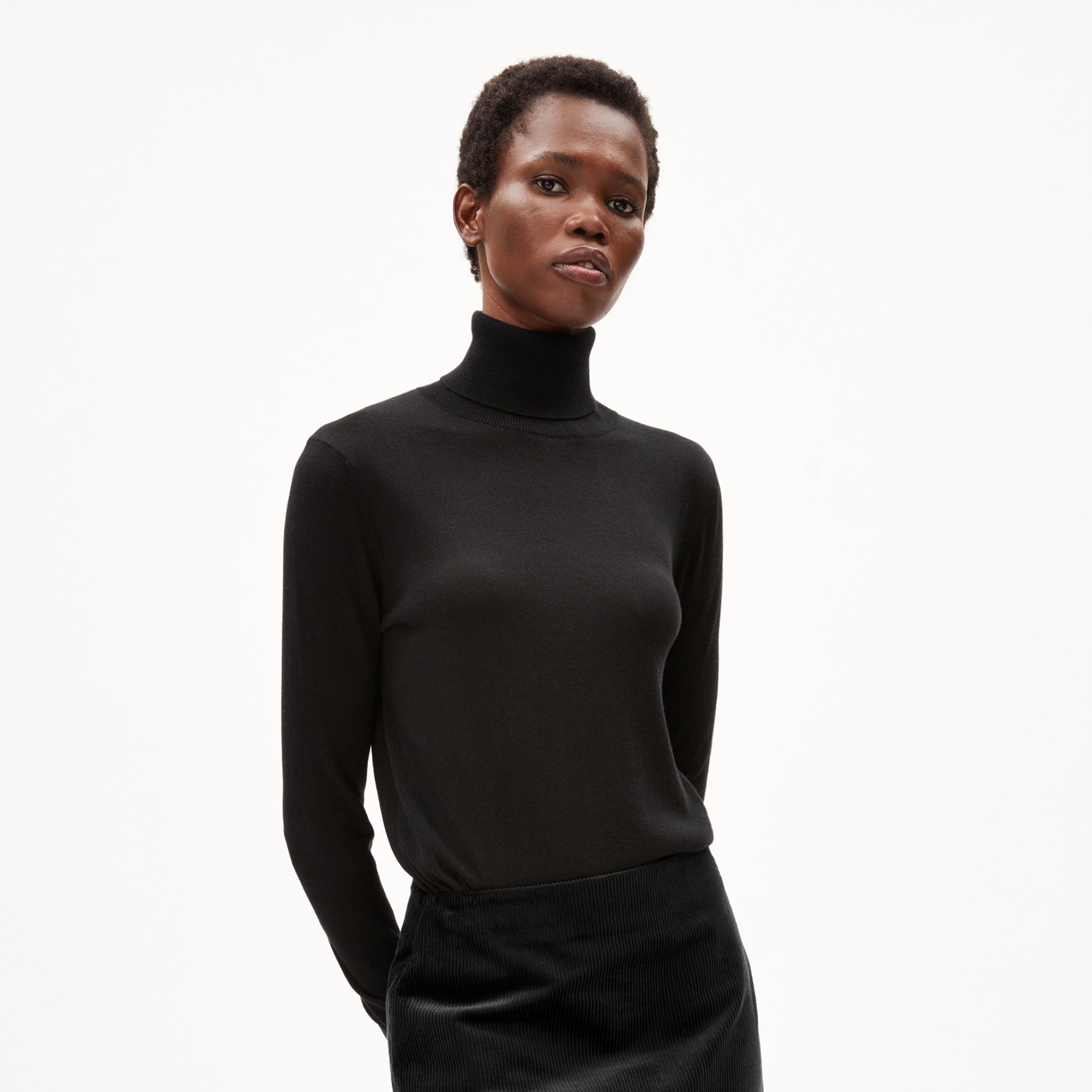 Person in schwarzem Rollkragenpullover vor hellem Hintergrund.