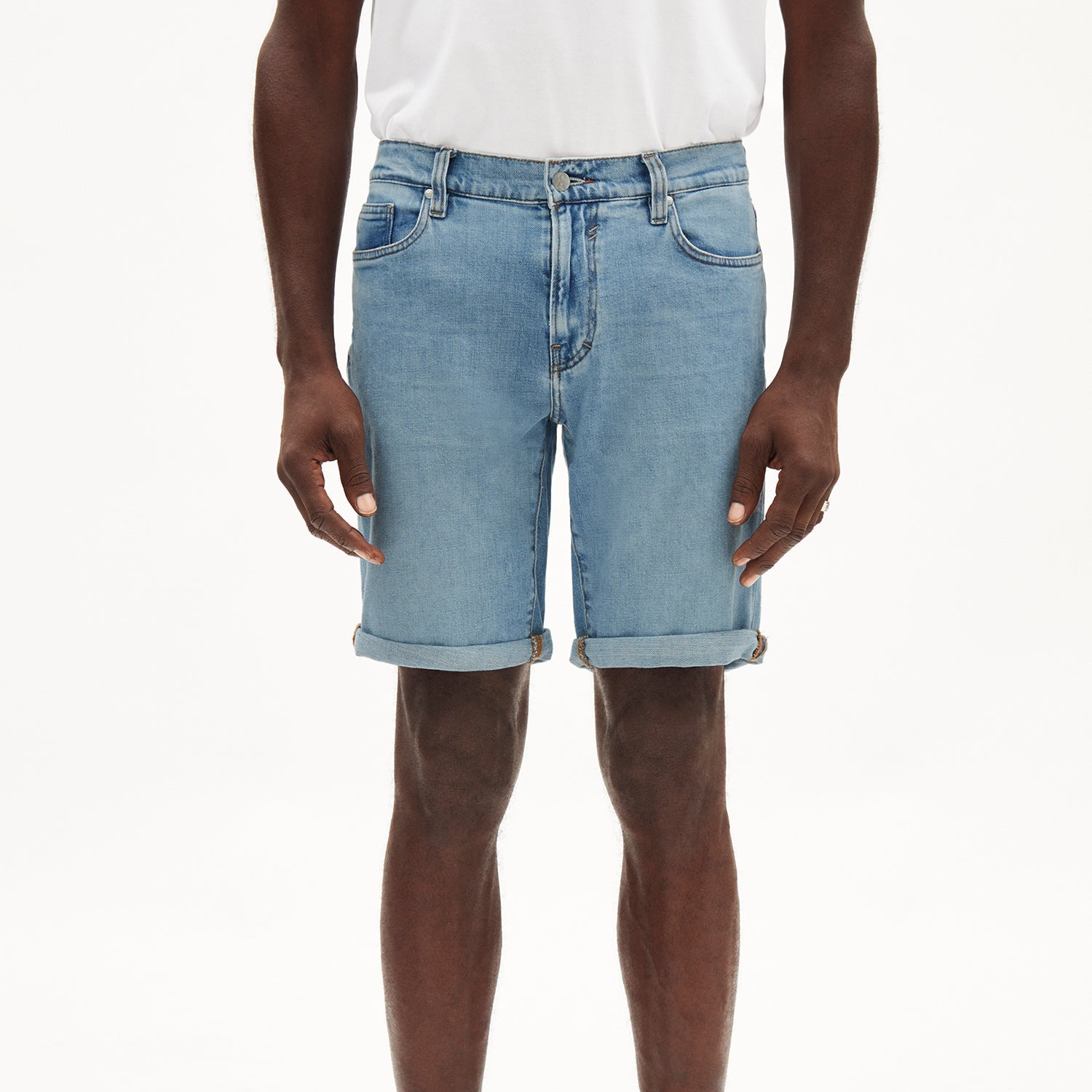Person trägt eine hellblaue Jeansshorts und ein weißes T-Shirt vor einem weißen Hintergrund.