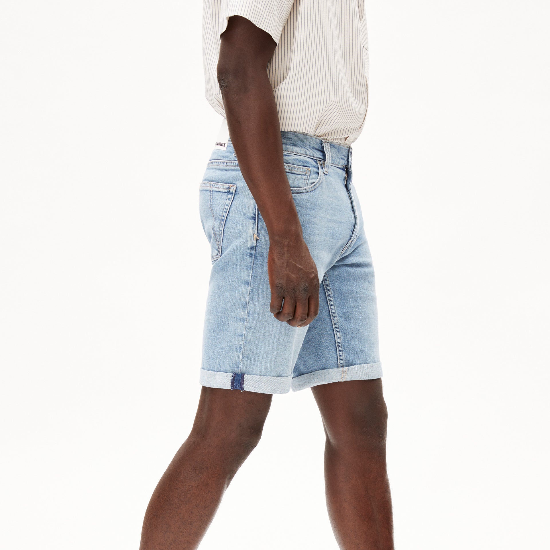 Person in hellblauen Jeansshorts und gestreiftem Hemd, seitlich gehend, auf weißem Hintergrund.