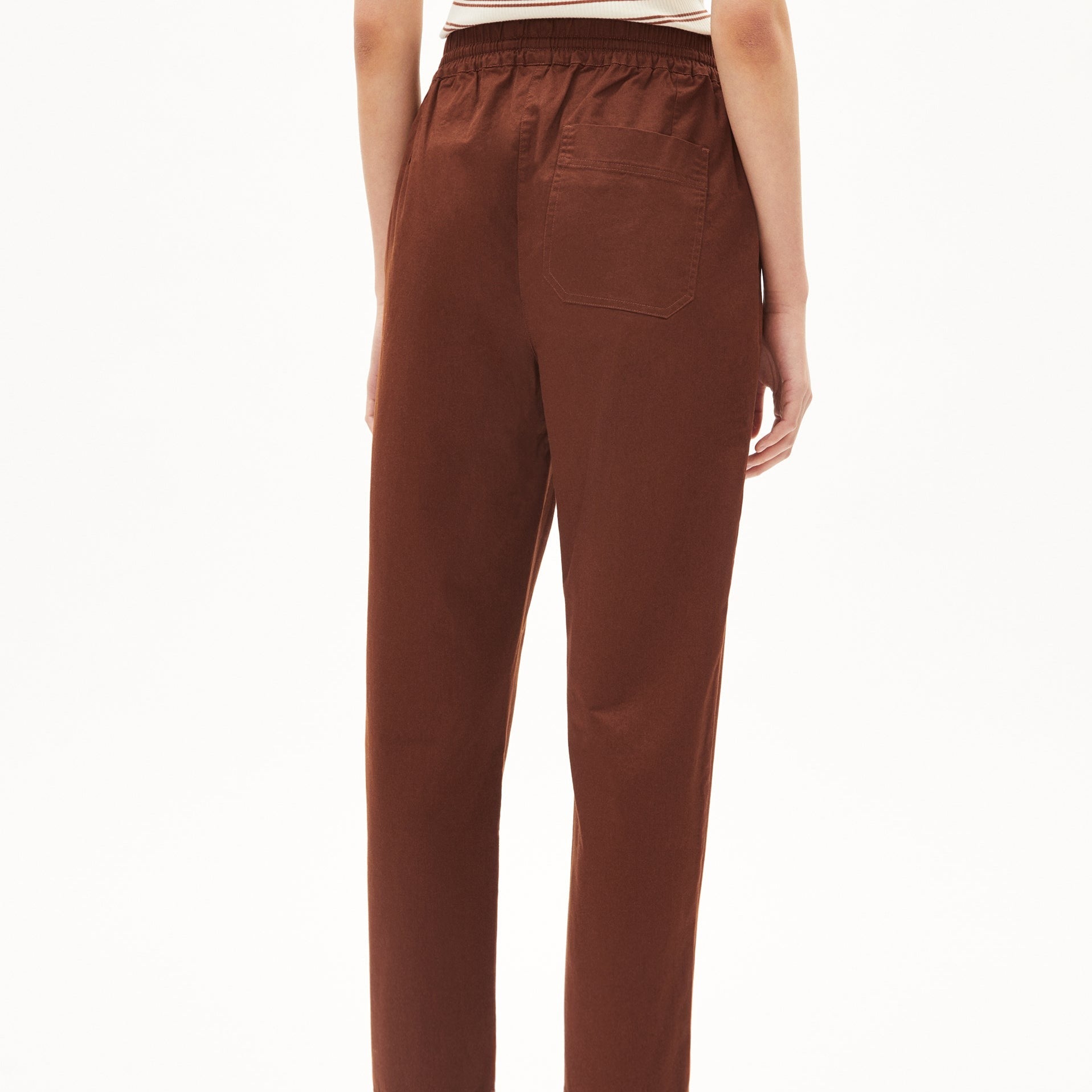 Rückansicht einer Person in brauner Hose mit elastischem Bund und aufgesetzter Gesäßtasche.