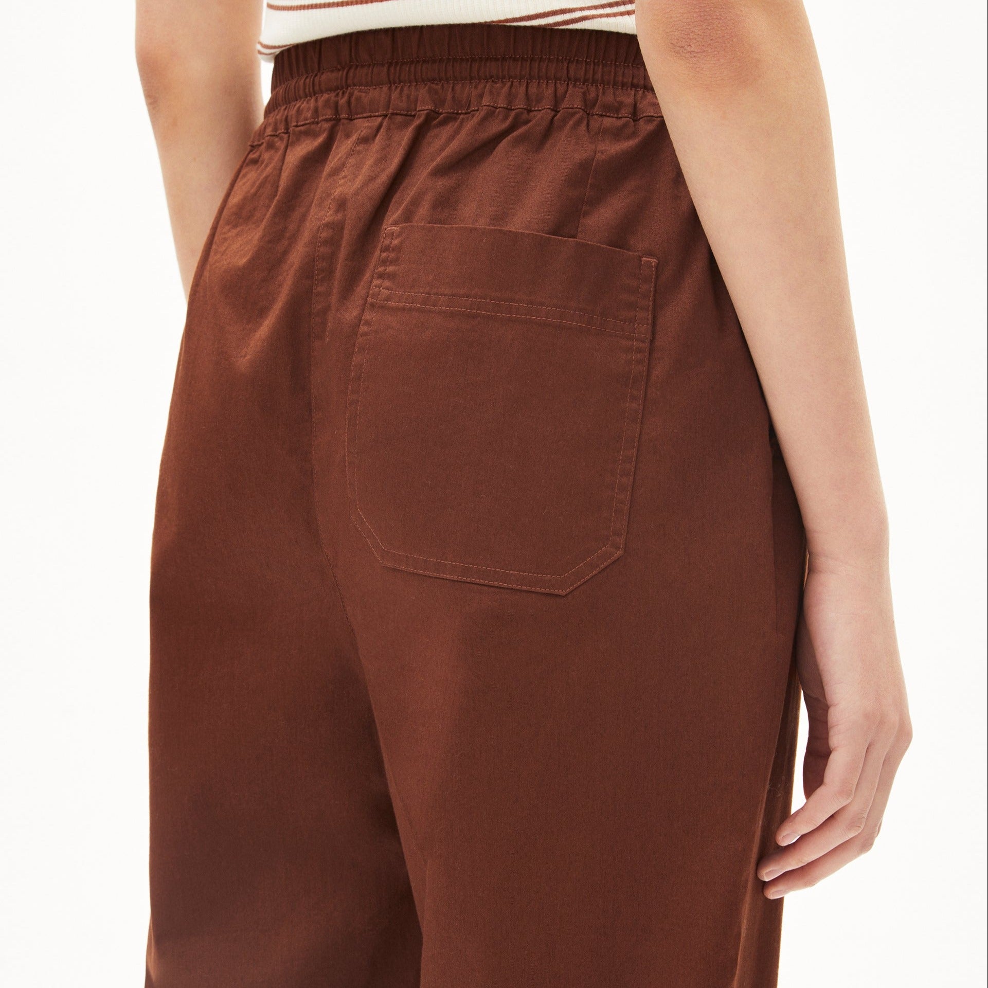 Nahaufnahme einer Person, die braune Hosen mit einer Gesäßtasche trägt, und einen gestreiften oberen Saum.