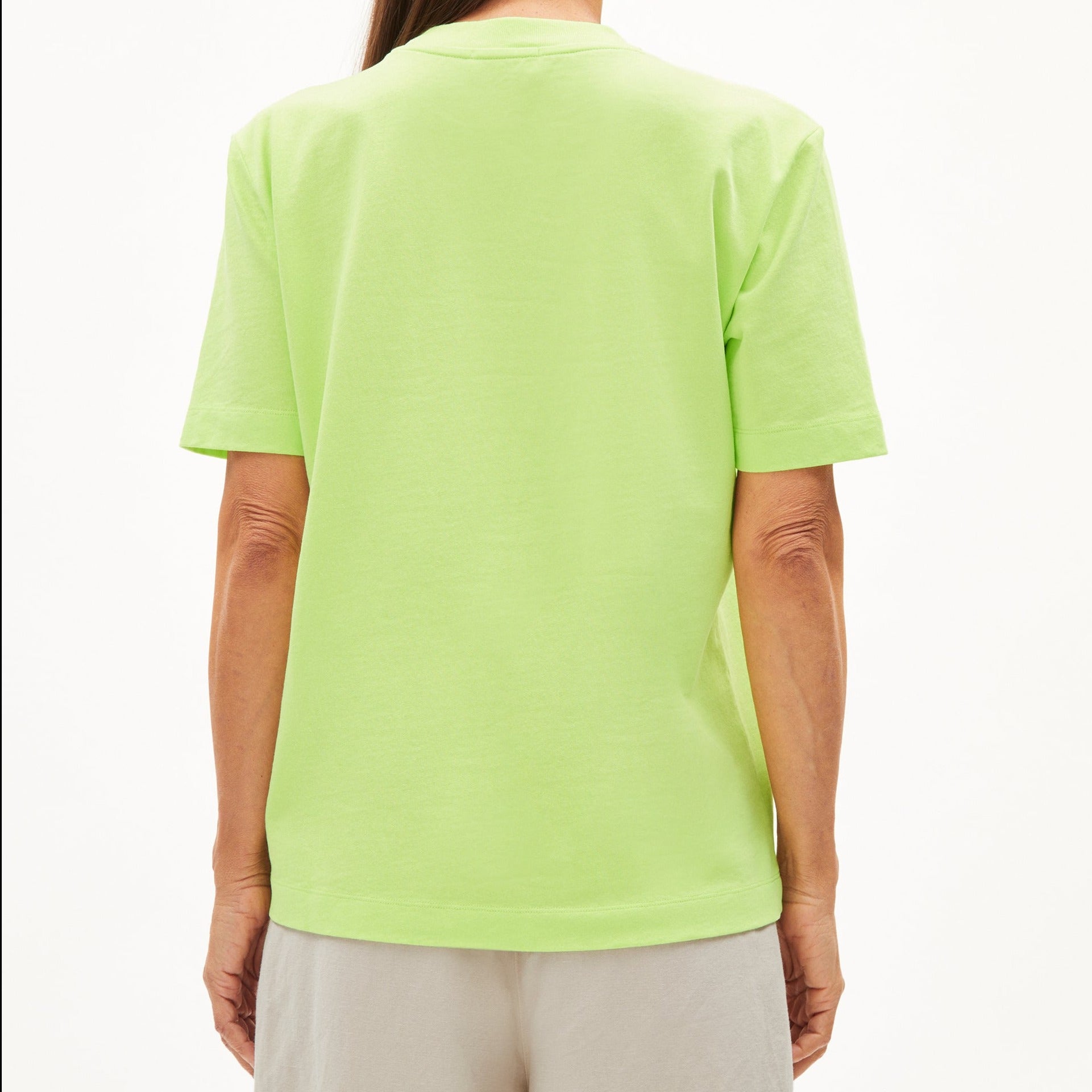 Person in einem hellgrünen T-Shirt und grauer Hose, von hinten fotografiert.