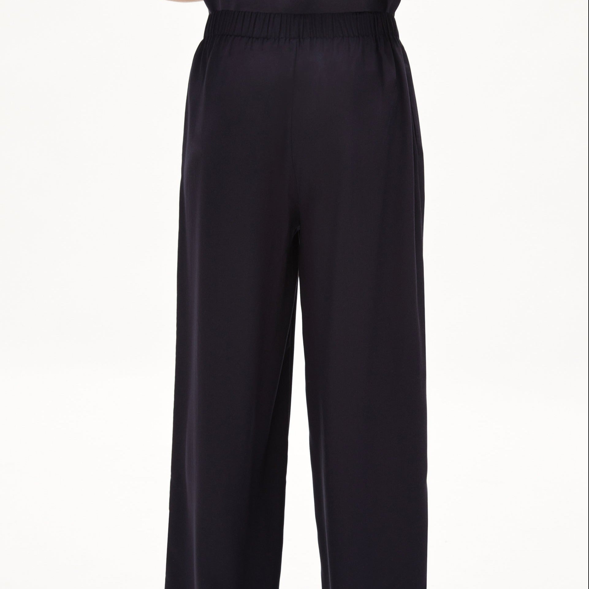 Eine schwarze, locker sitzende Hose mit elastischem Bund vor weißem Hintergrund.