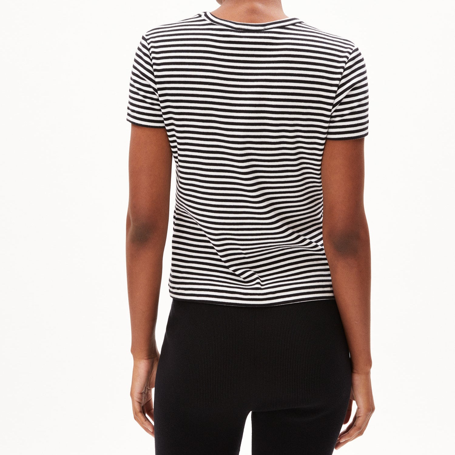 Person in a black and white striped shirt and black pants, seen from behind against a white background.