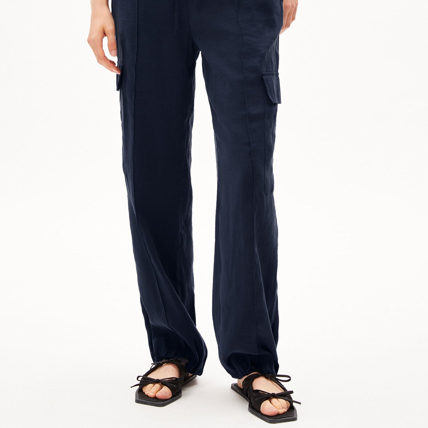 Person trägt eine dunkelblaue Hose mit seitlichen Taschen und schwarze Sandalen.