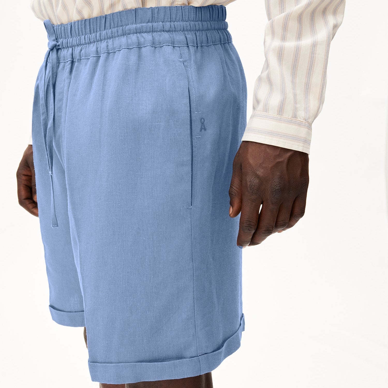 Ein Mann trägt eine hellblaue Shorts mit einem elastischen Bund und einem gestreiften Hemd.