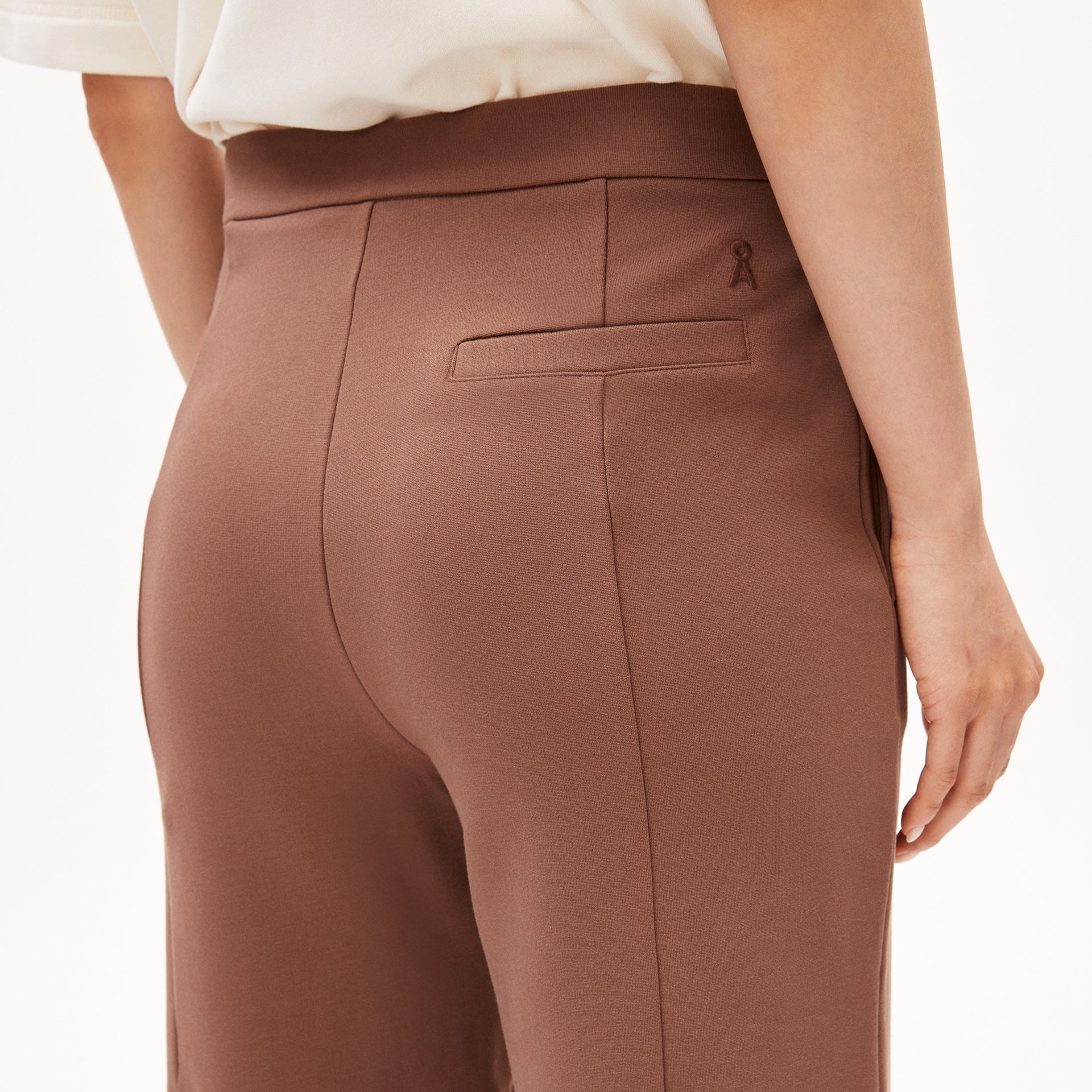 Nahaufnahme einer Person, die eine braune Hose trägt; die weiße Oberteilkante ist sichtbar.