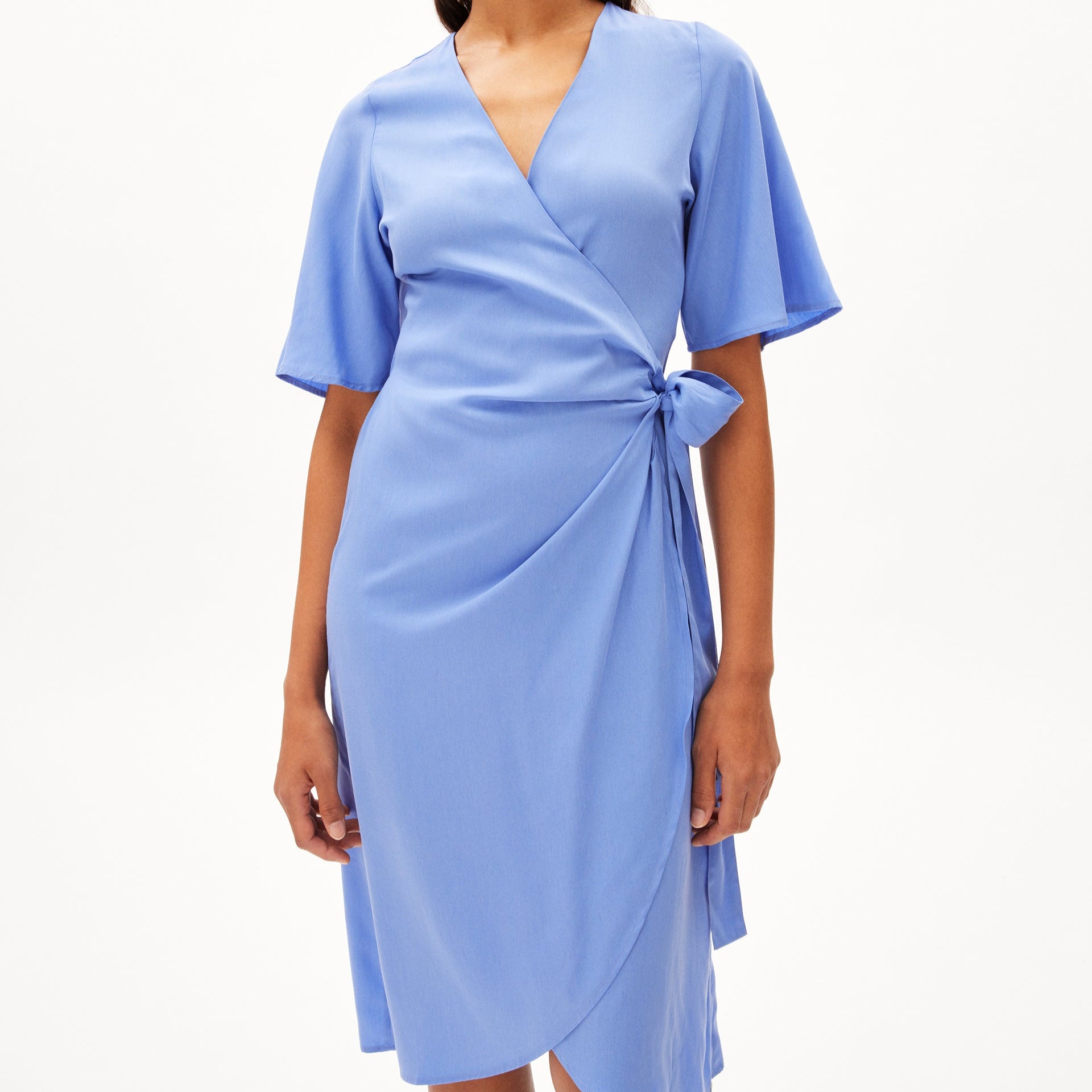 Eine Person trägt ein himmelblaues Wickelkleid mit kurzen Ärmeln und Schleife an der Taille.