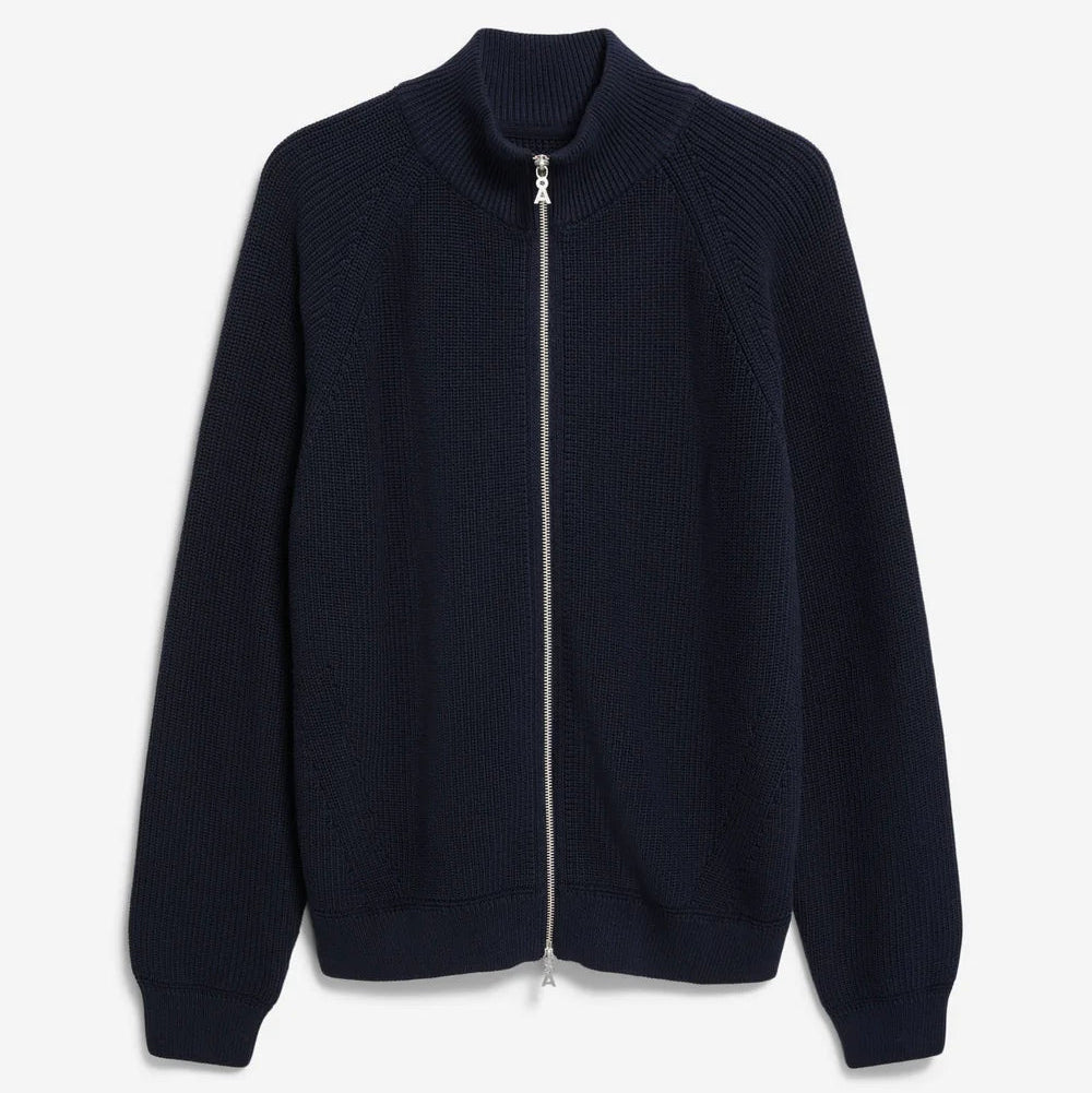 Eine marineblaue, langärmelige Strickjacke mit hohem Kragen und einem durchgehenden silbernen Reißverschluss auf der Vorderseite, flach auf weißem Hintergrund dargestellt.