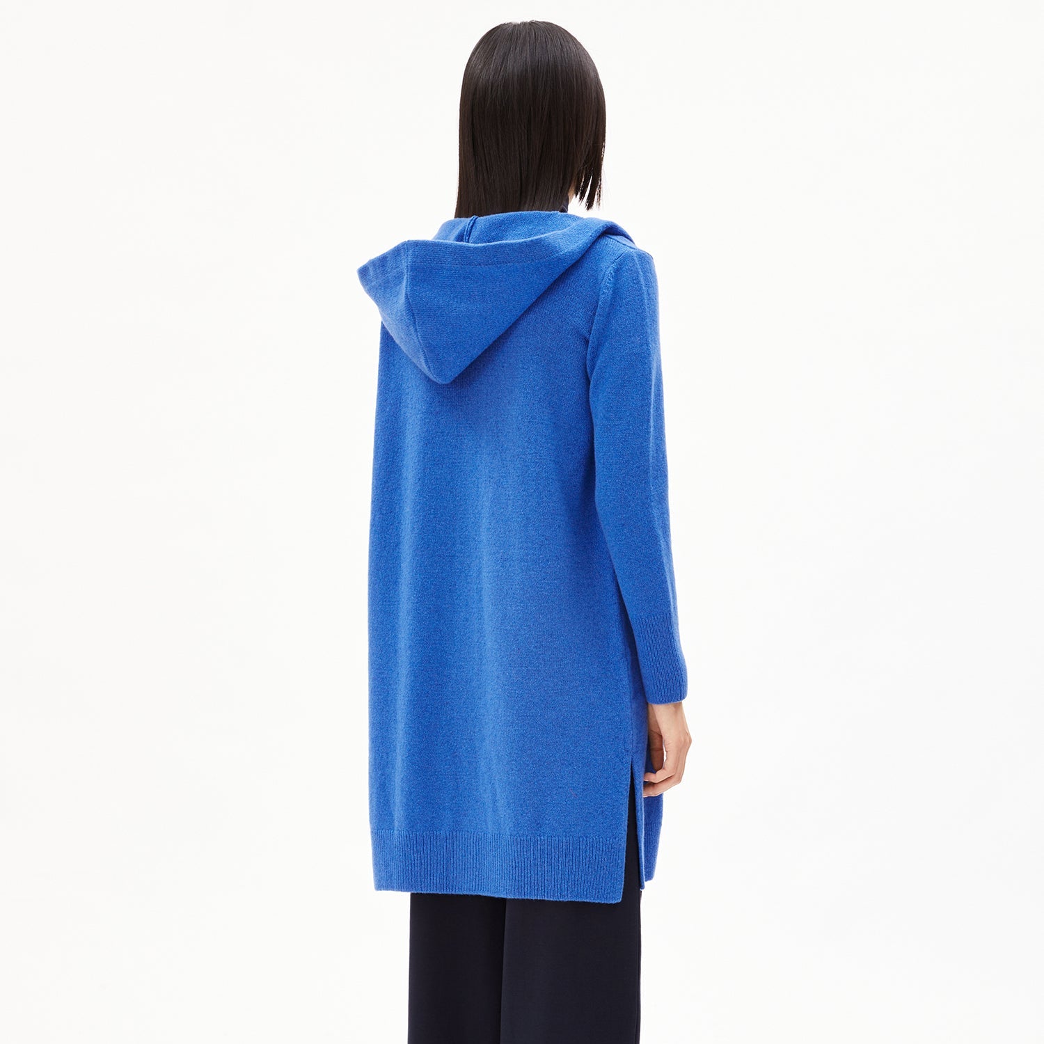 Person in einem langen, blauen Hoodie von hinten, vor einem weißen Hintergrund.