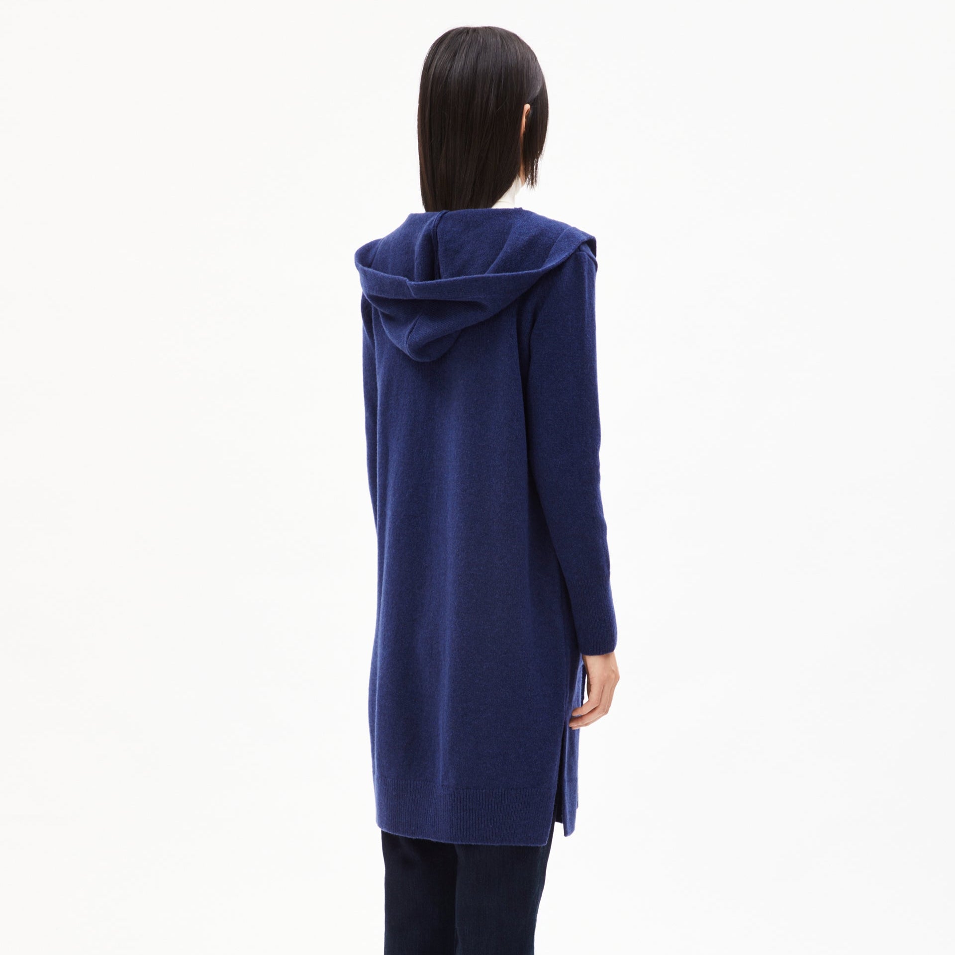 Person in dark blue, hooded cardigan, viewed from behind against a plain white background.