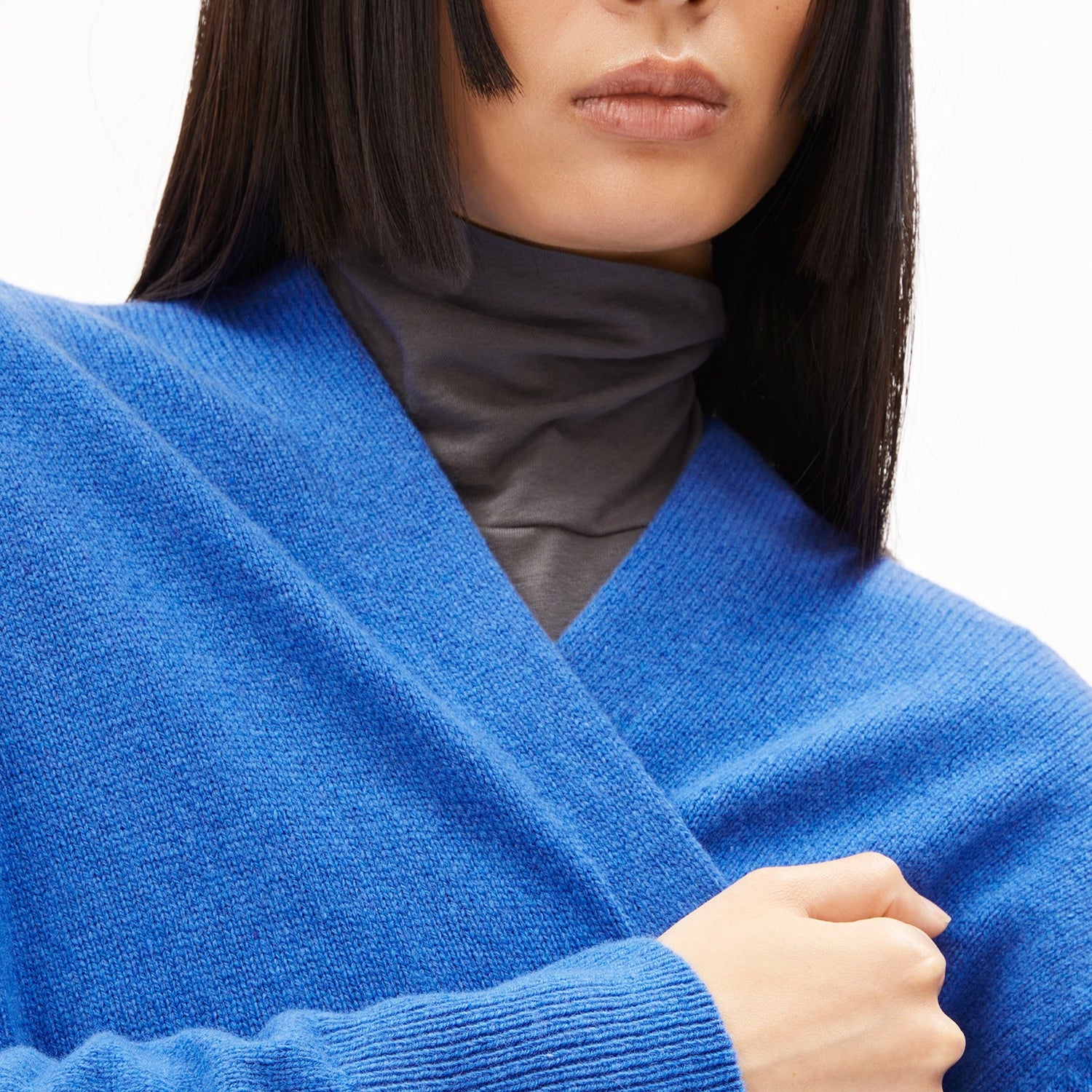 Frau mit schulterlangem Haar trägt einen blauen Pullover und ein graues Rollkragenshirt.