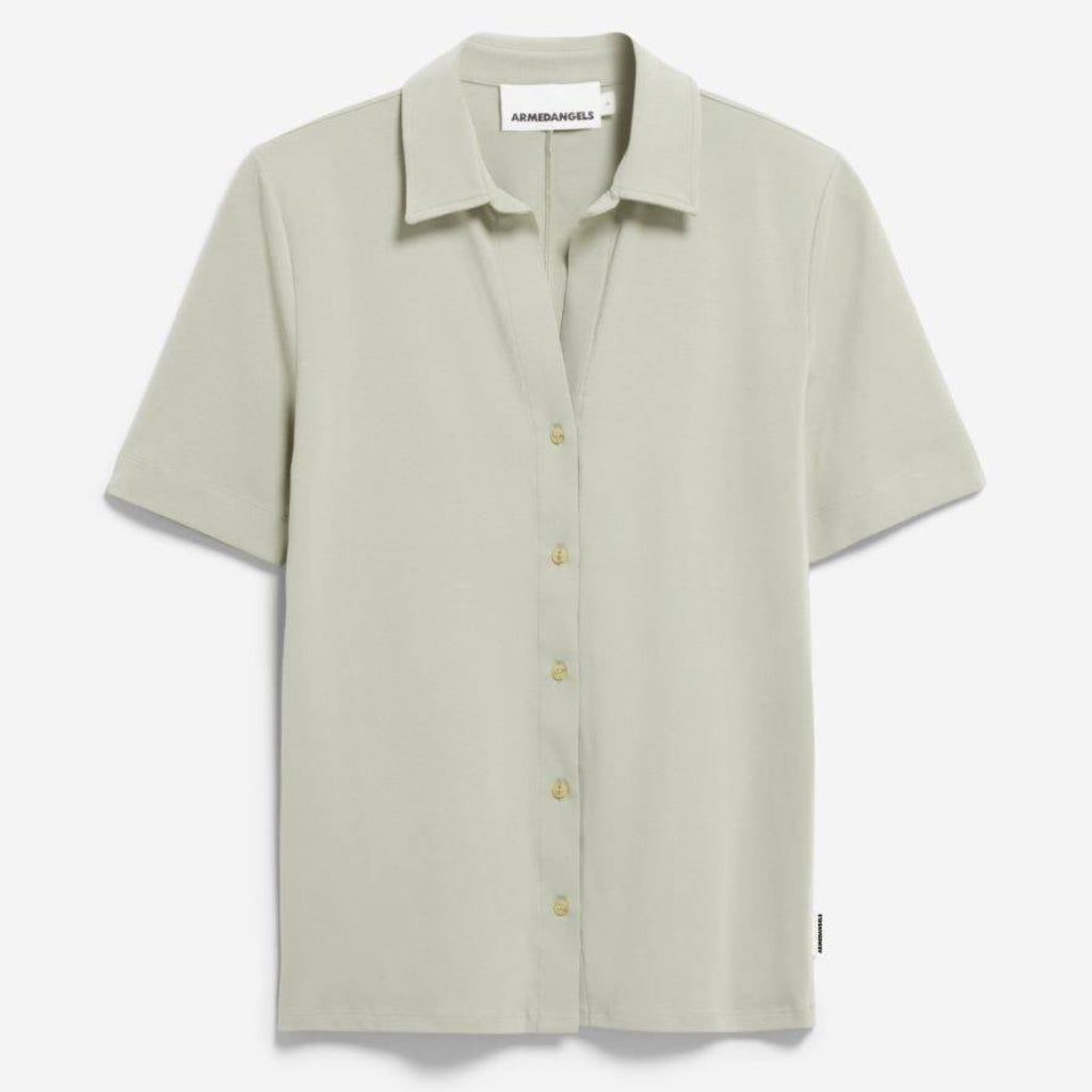 Ein helles, salbeigrünes, kurzärmeliges Button-up-Hemd mit Kragen, das vor einem schlichten weißen Hintergrund steht. Das Hemd hat eine lockere Passform und ein einfaches Design, mit Knöpfen auf der Vorderseite.