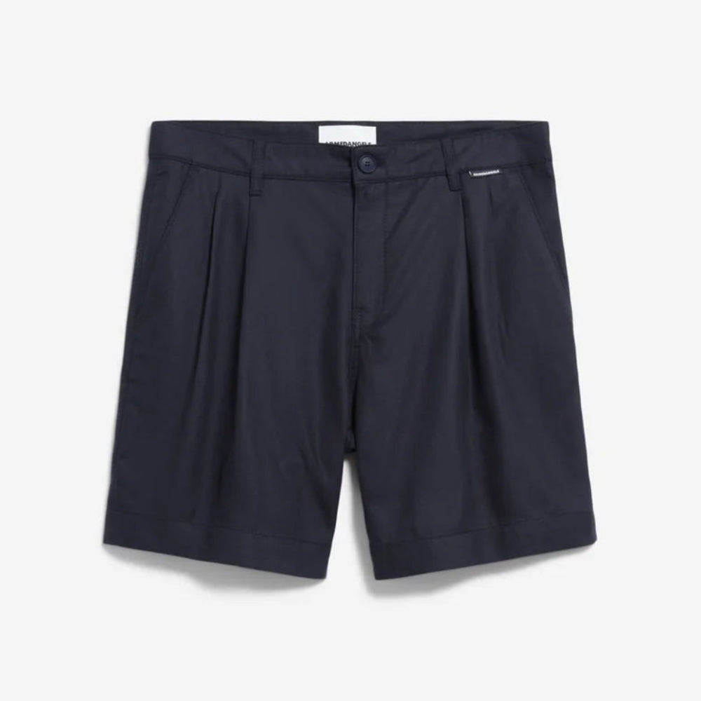 Ein Paar dunkle, marineblaue, maßgeschneiderte Shorts mit Bundfalten, Seitentaschen und einem Knopfverschluss, flach auf weißem Hintergrund gelegt.