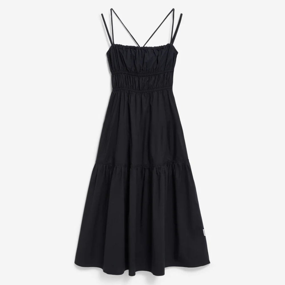 Ein ärmelloses schwarzes Midikleid mit dünnen Spaghettiträgern und einem taillierten, gerüschten Mieder. Der Rock ist gerafft und fällt locker bis zur Mitte der Wade.