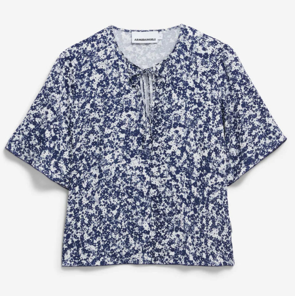 Kurzärmelige Bluse mit blau-weißem Blumendruck, rundem Halsausschnitt und kleinem Bindeband auf der Vorderseite auf weißem Grund.