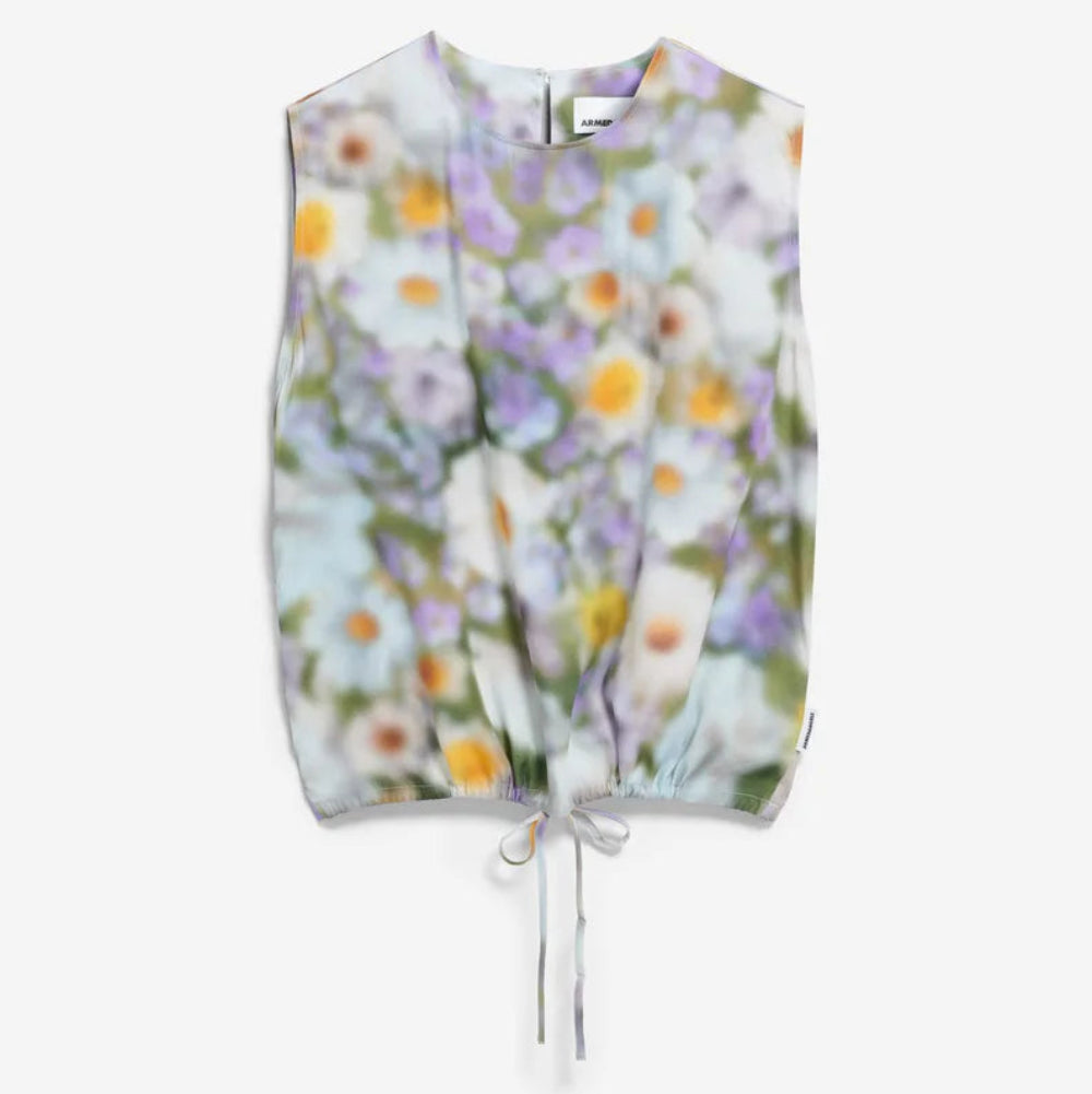 Ärmelloses Oberteil mit Kordelzug in der Taille, mit einem weichen, verschwommenen Blumendruck in Pastellfarben, darunter Weiß, Gelb und Lila, auf einem einfarbig weißen Hintergrund.